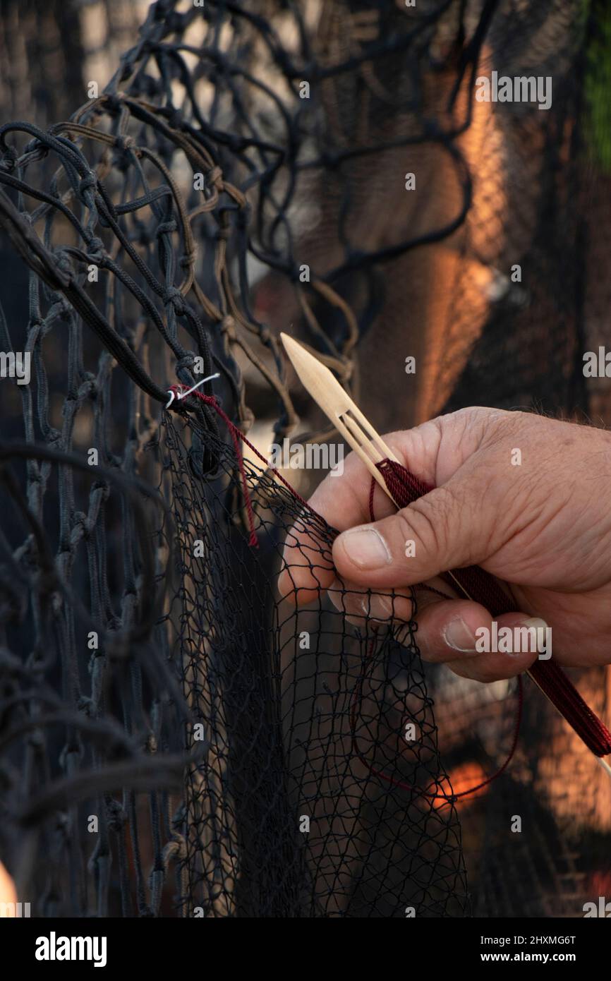 Fischer reparieren das Fischernetz , arbeiten Hand mit Holznadel Nahaufnahme Detail Stockfoto