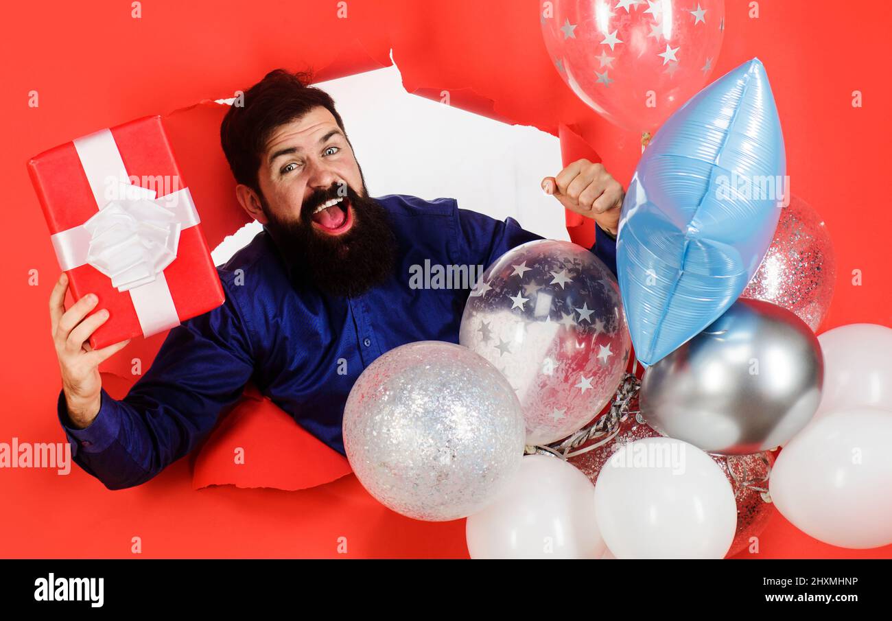 Glücklicher Mann mit aufblasbaren Ballons und präsent. Partylaune. Vorbereitung auf den Geburtstag. Geschenkbox. Stockfoto