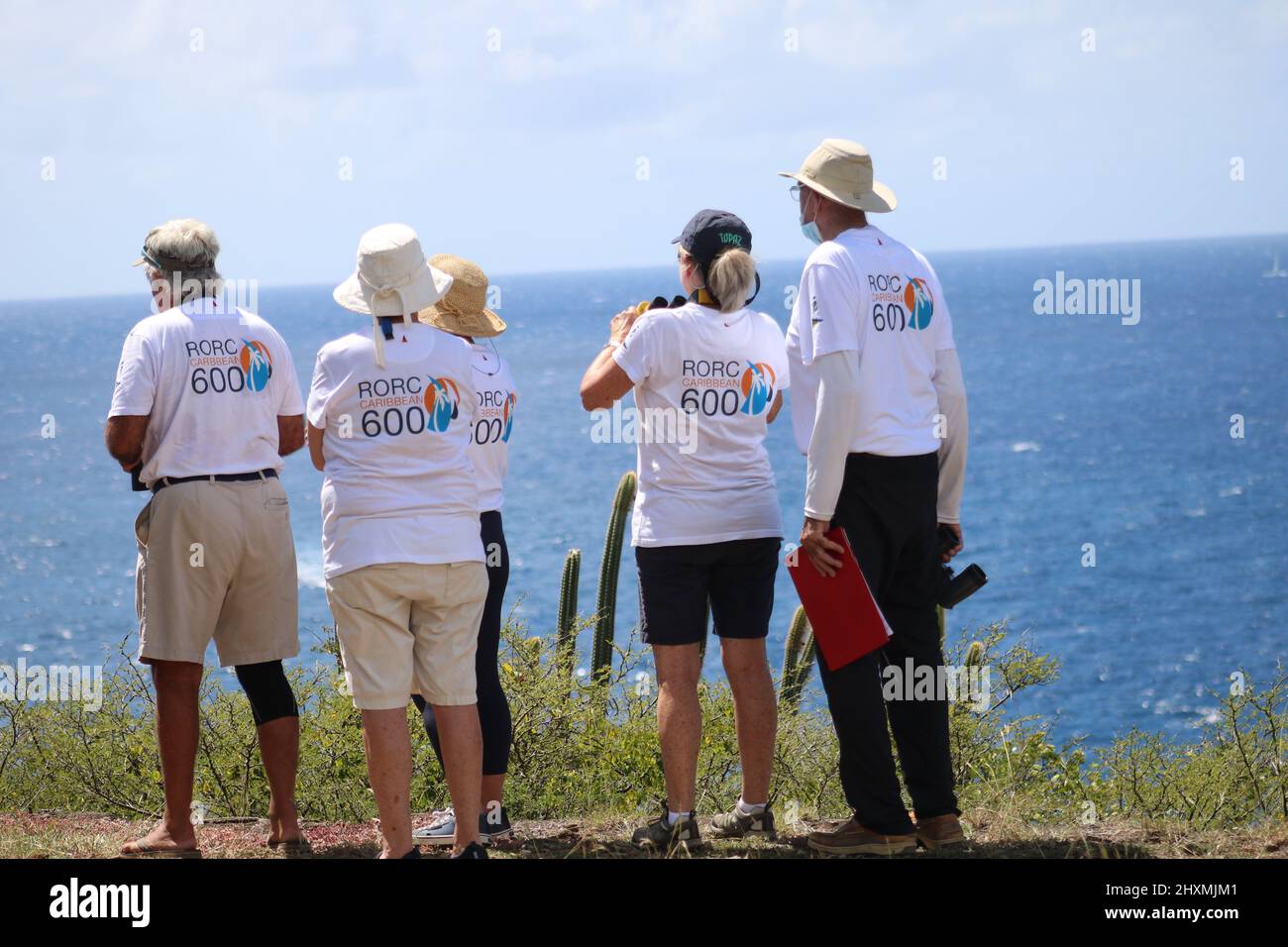 Freiwillige in T-Shirts bereiten sich auf den Start des Royal Ocean Racing Club Caribbean 600-Rennens am Aussichtspunkt über dem englischen Hafen vor Stockfoto