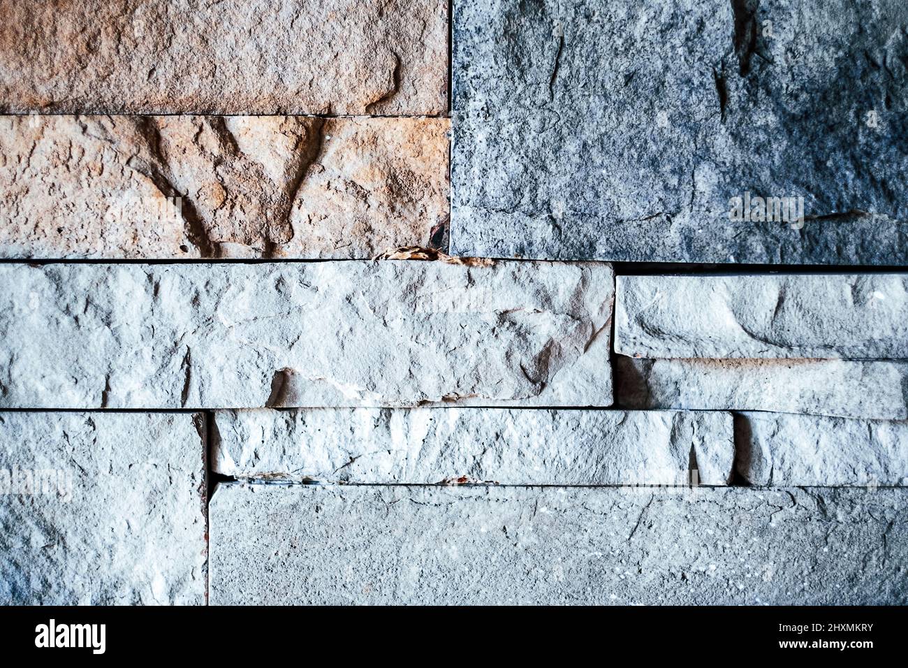 Eine schwach beleuchtete strukturierte Wand aus bunten Steinziegeln Stockfoto