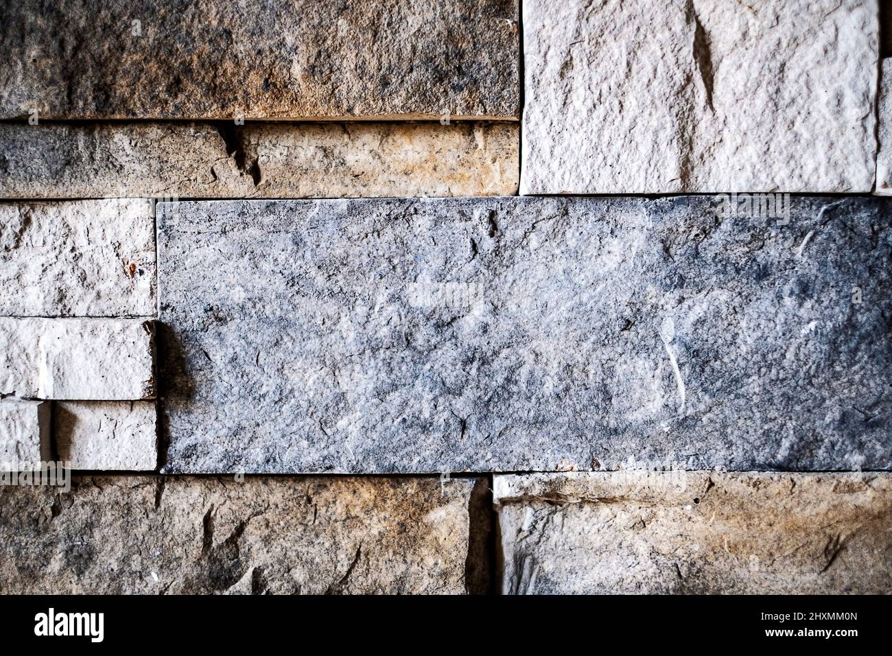 Eine schwach beleuchtete strukturierte Wand aus bunten Steinziegeln Stockfoto
