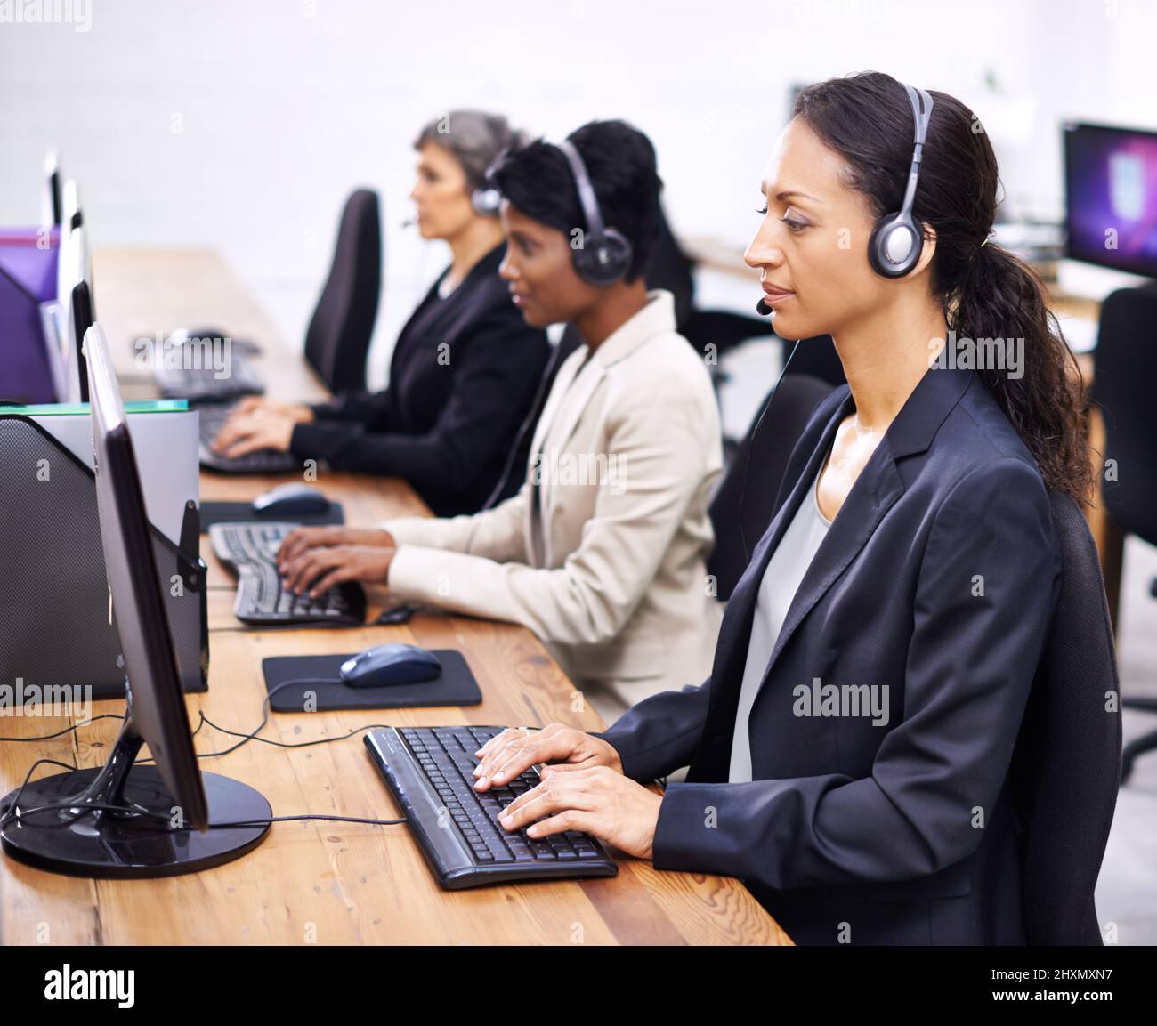 Sie haben immer einen tollen Service geboten. Eine kurze Aufnahme von drei Callcenter-Sprecherinnen, die Headsets tragen. Stockfoto