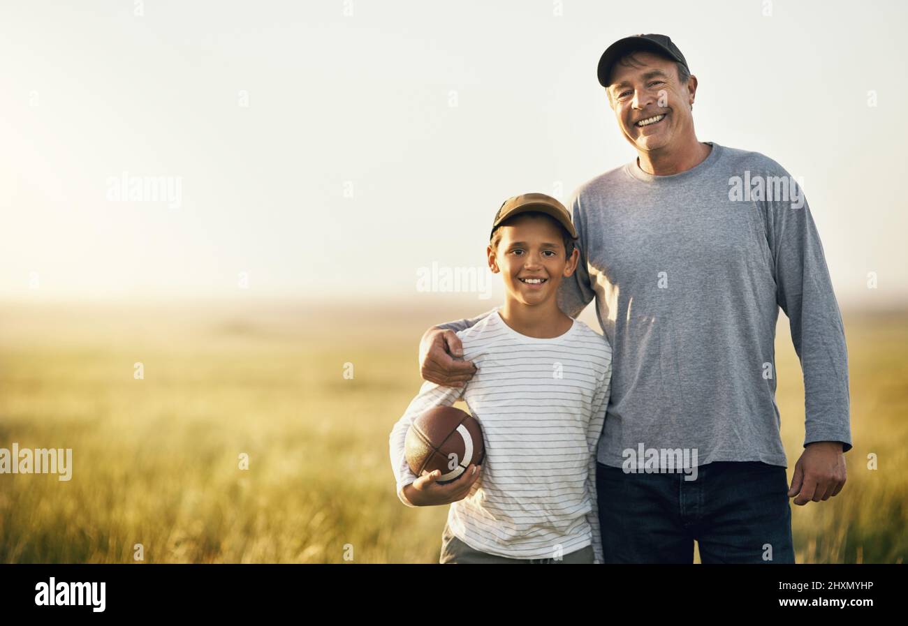 Wir verbinden uns immer mit Fußball. Aufnahme von Vater und Sohn, die auf einem offenen Feld Fußball spielen. Stockfoto