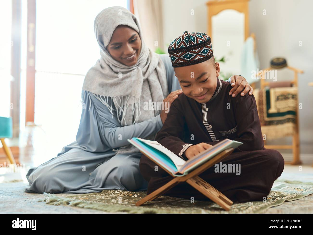 Liebe ist die höchste Form der Kommunikation. Aufnahme einer jungen muslimischen Mutter und ihres Sohnes beim Lesen in der Lounge zu Hause. Stockfoto