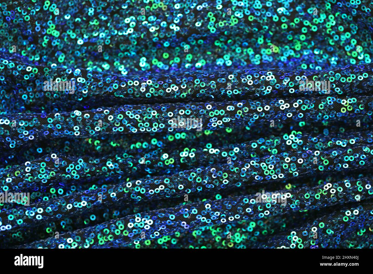 Stoff mit schimmernden Pailletten.Grün und blau Pailletten Hintergrund.Schuppen Hintergrund.glänzende Oberfläche in blauen und grünen Tönen. Schillernde Pailletten Textur. Stockfoto