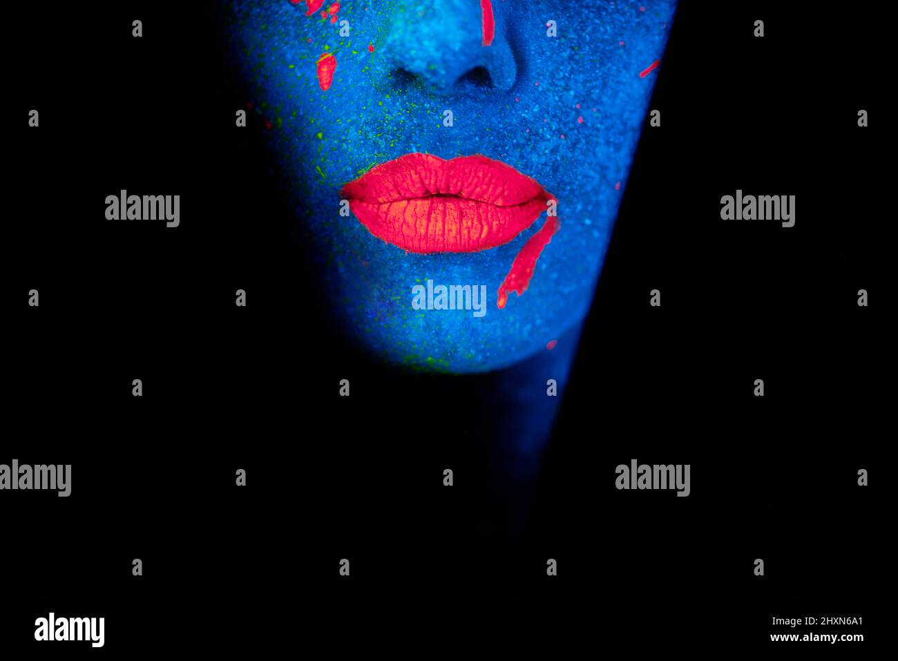 Leuchtende Lippen. Aufnahme einer jungen Frau, die mit Neonfarbe auf ihrem Gesicht posiert. Stockfoto