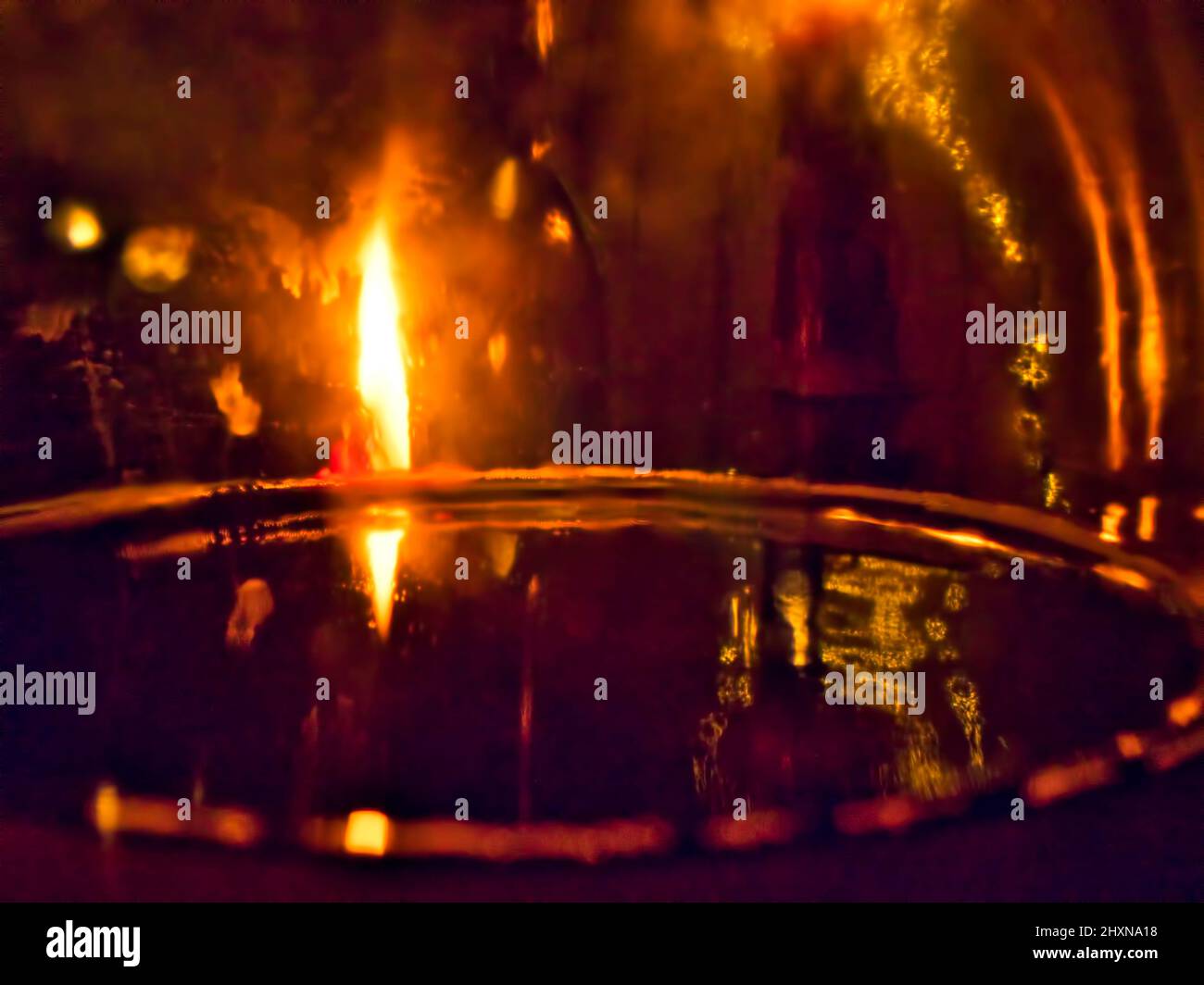 Seltsame Szene mit einem düsteren atmosphärischen, abstrakten Look mit Kerzen und Wasserspiegelungen. Stockfoto