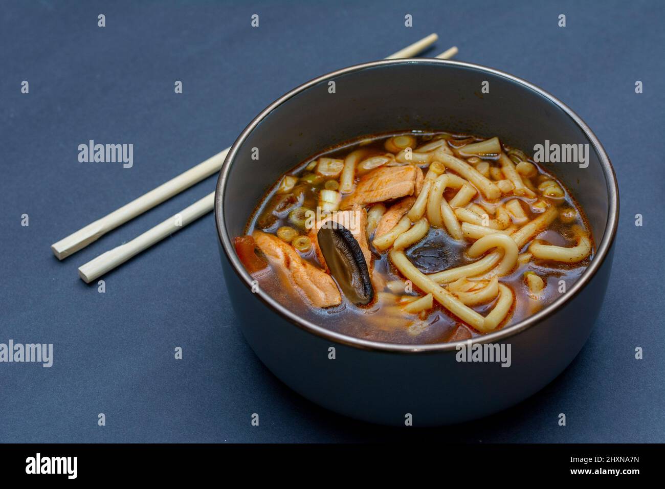 Tom Yam Suppe mit Lachs und Gemüse wie Kirschen, Chilly, Zitronengras auf grauem Hintergrund Stockfoto