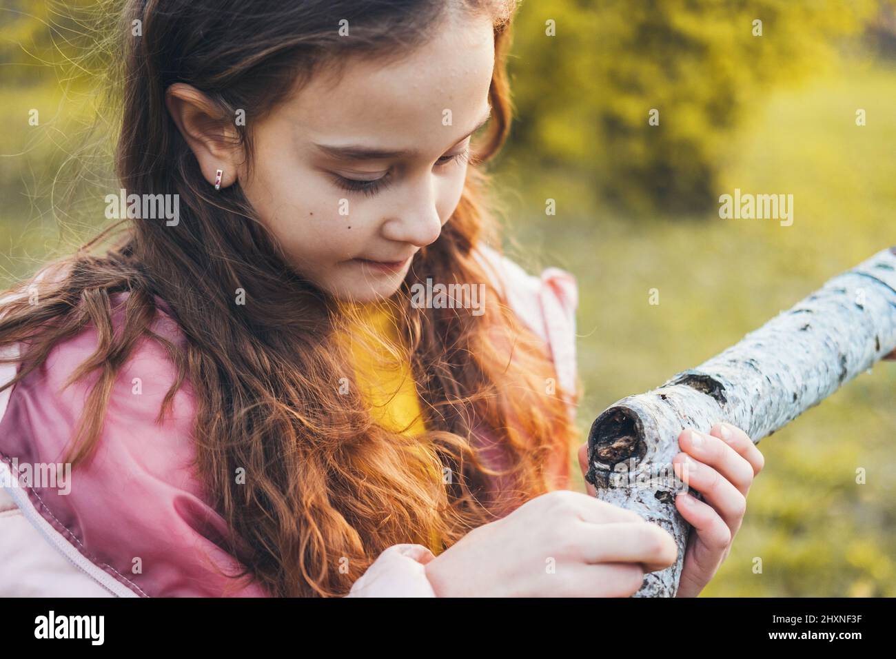 Nahaufnahme eines kleinen Mädchens, das mit einem Baum spielt, Herbst im Park. Die Welt entdecken. Familientag. Stockfoto