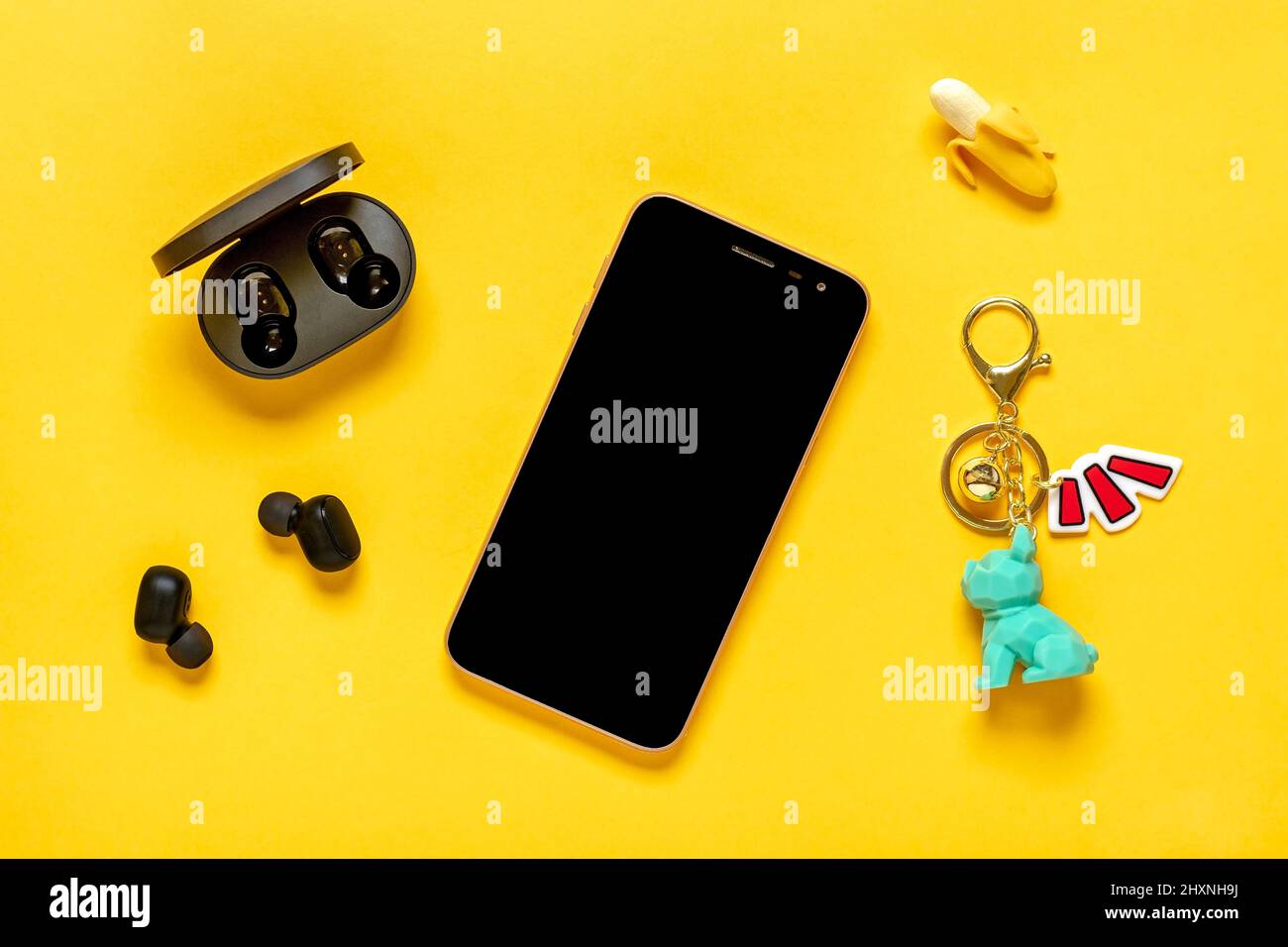 Smartphone mit schwarzem Bildschirm und kabellosen Kopfhörern redmi Airdots, Ladekapsel auf gelbem Hintergrund Mock Up Flat Lay Draufsicht Social Media, Digit Stockfoto