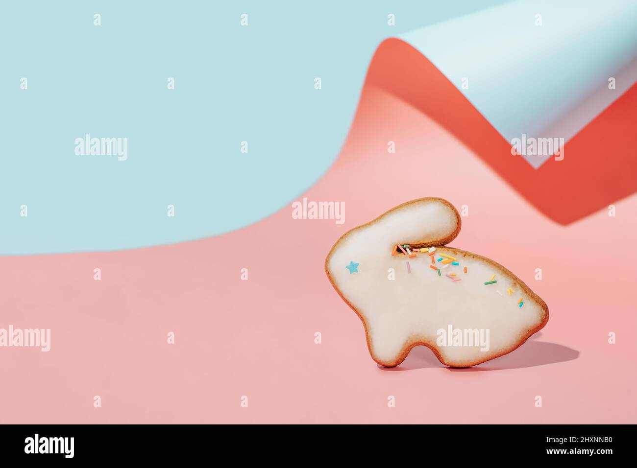 Osterhase Plätzchen auf rosa und blau geschwungenen Papier pastellfarbenen Hintergrund mit Schatten. Happy Easter Day Konzept. Minimales Osterkonzept. Platz für Text kopieren. Ostern Kochen Backing Hintergrund. Stockfoto