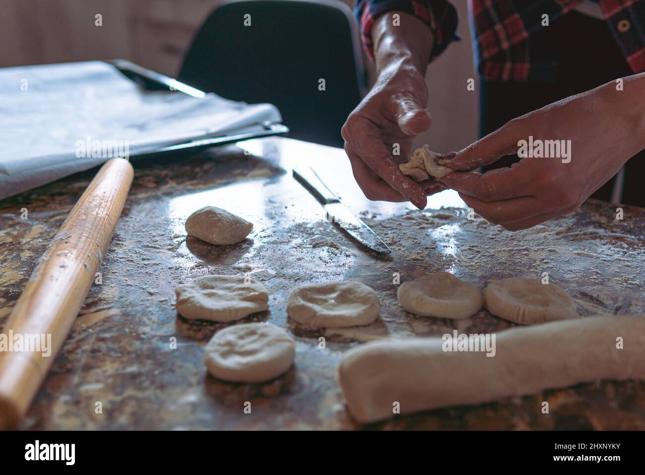 Frau, die Kuchen, auch bekannt als Somsa oder Samosa, zu Hause kocht und aus Teig Nahrung zubereitet. Nahaufnahme des selektiven Fokus Stockfoto