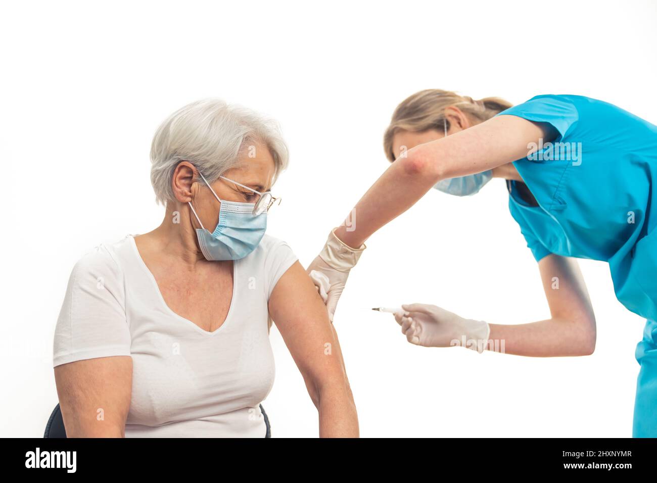 Zwei kaukasische Menschen - ältere Rentnerin und eine Krankenschwester - der Prozess der Impfung auf weißem Hintergrund. Speicherplatz kopieren. Hochwertige Fotos Stockfoto