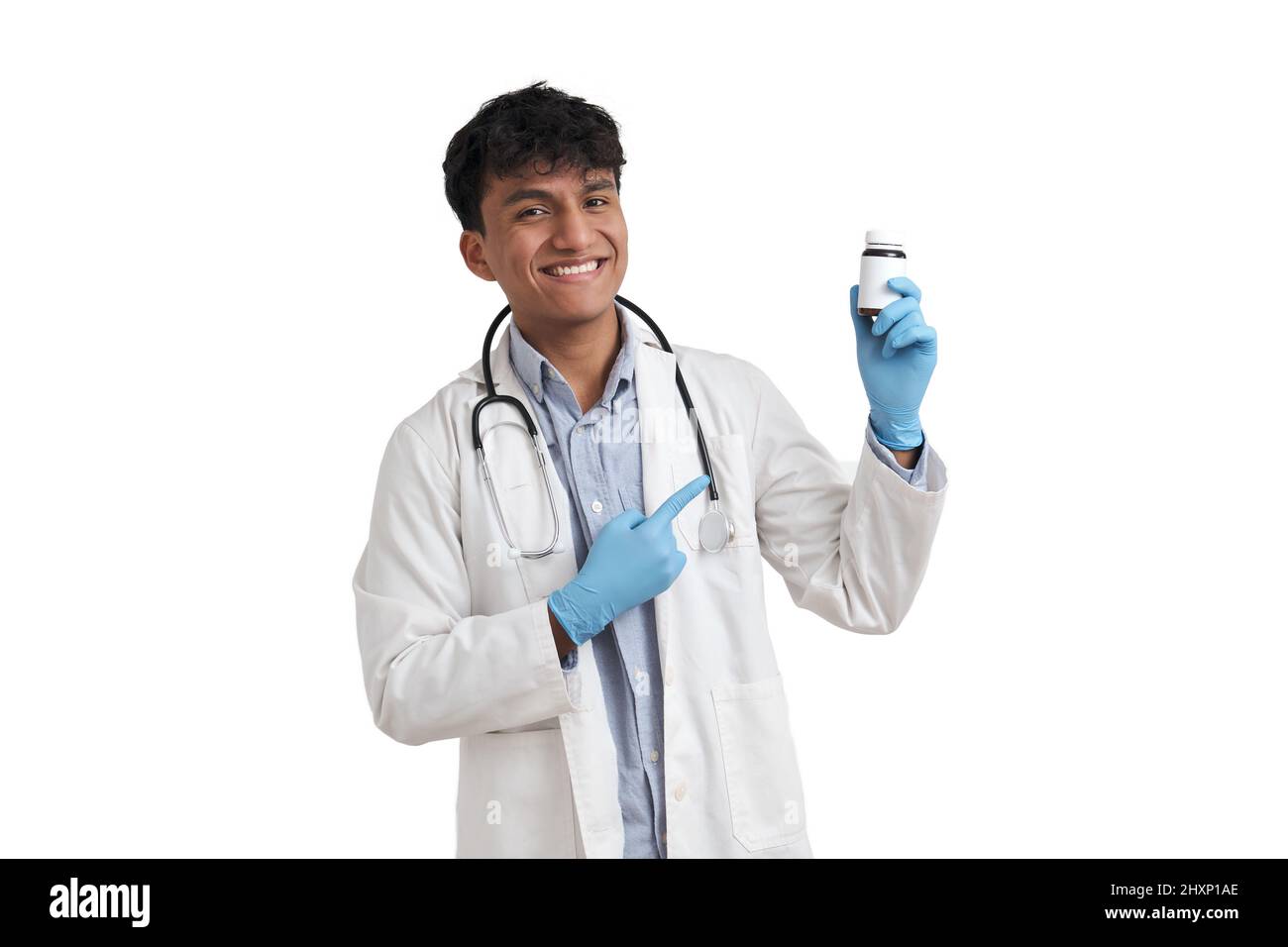 Junger peruanischer Arzt lächelt und zeigt isoliert auf eine Pillenflasche. Stockfoto