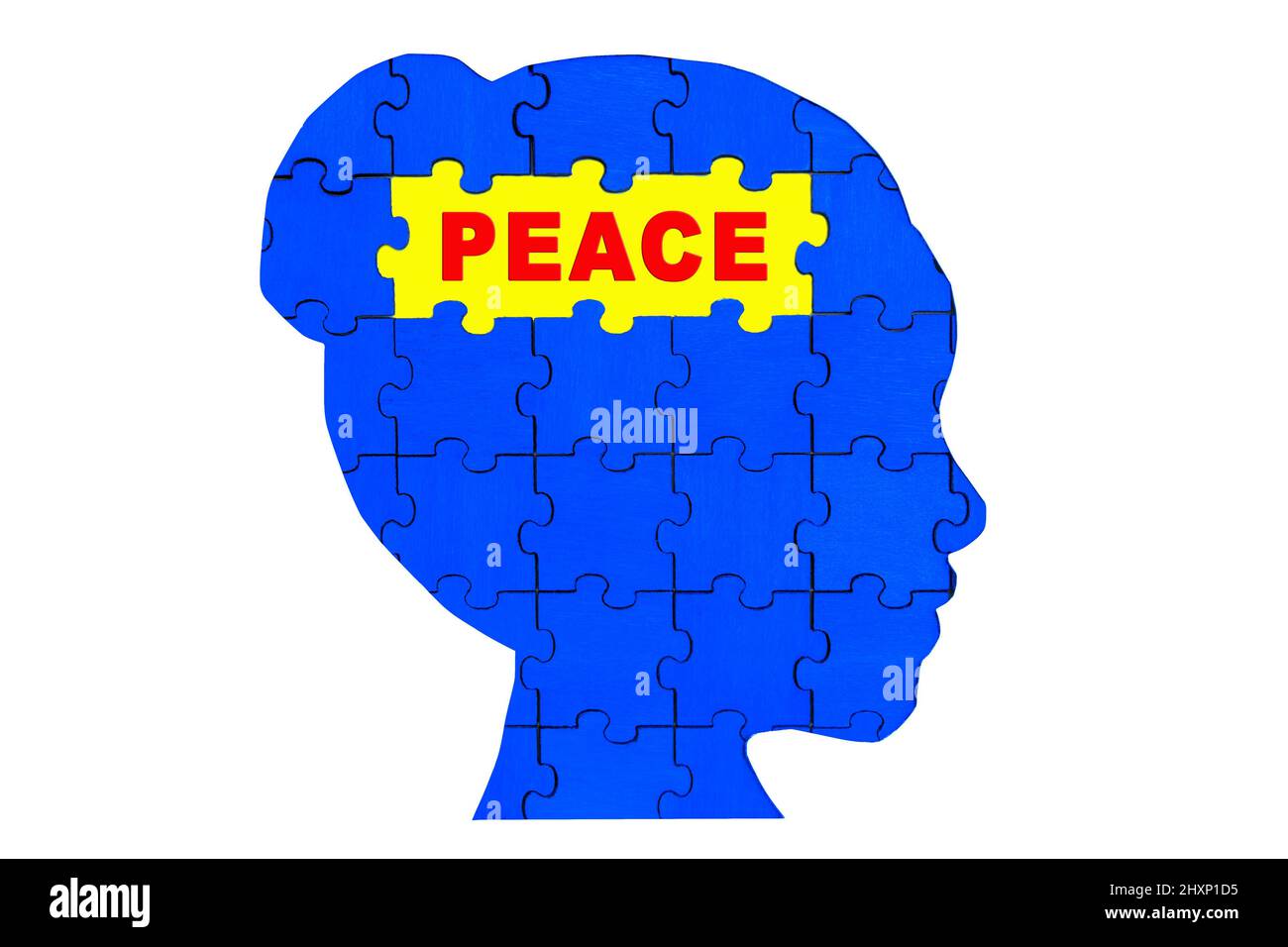 Silhouette eines weiblichen Kopfprofils aus hölzernen Puzzleteilen, die blau und gelb lackiert sind und Frieden lesen. Stockfoto