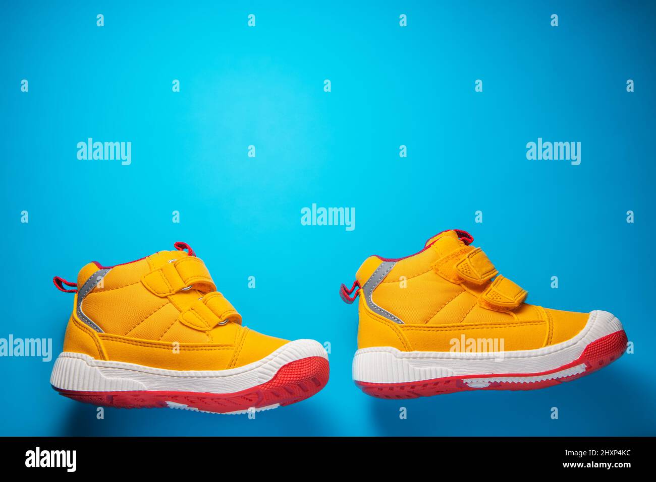 Gelbe Babyschuhe. Kinder Sport Sneaker isoliert auf blauem Hintergrund Stockfoto