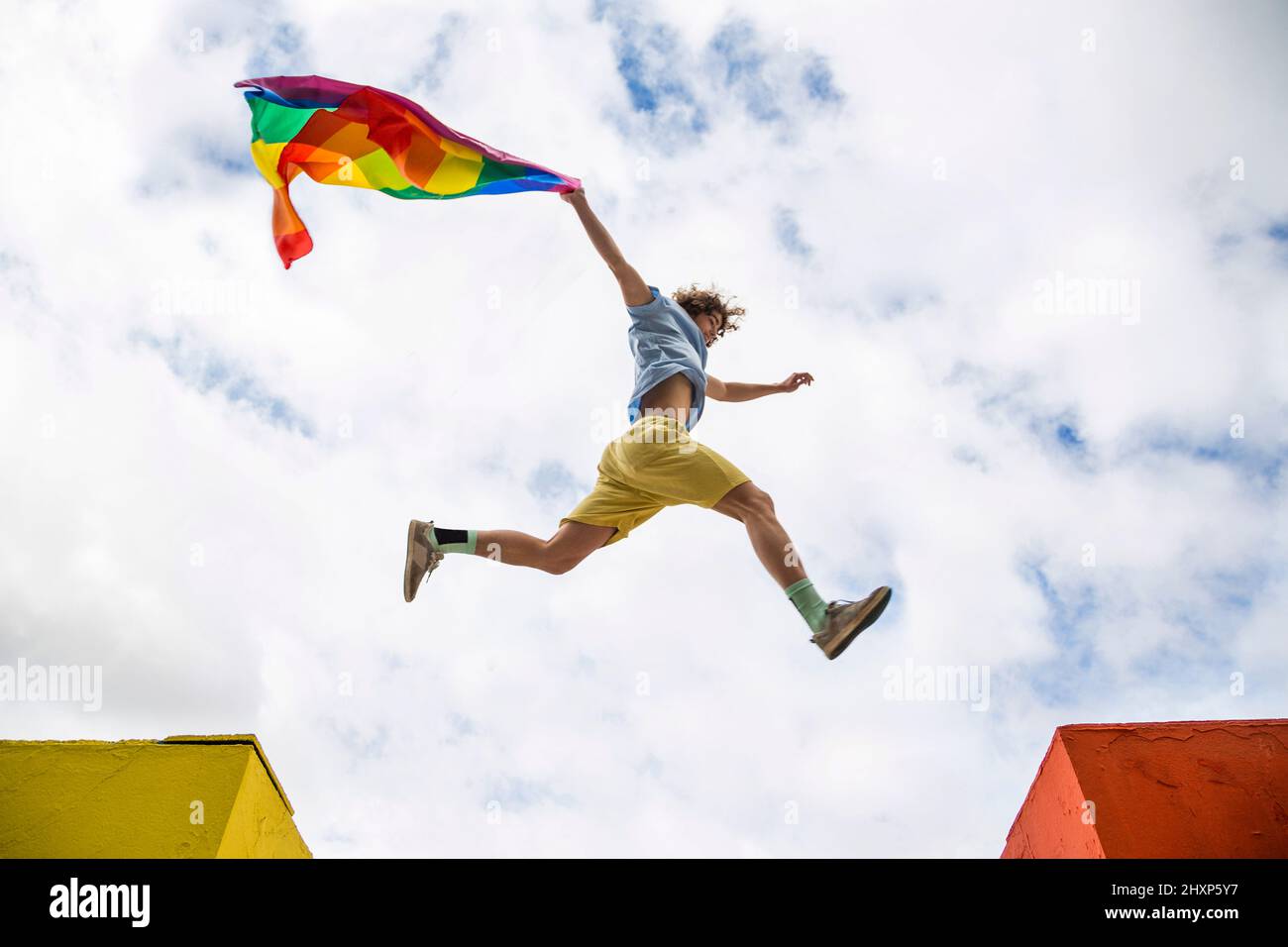 Junger Mann, der mit der Flagge des Gay Pride springt Stockfoto