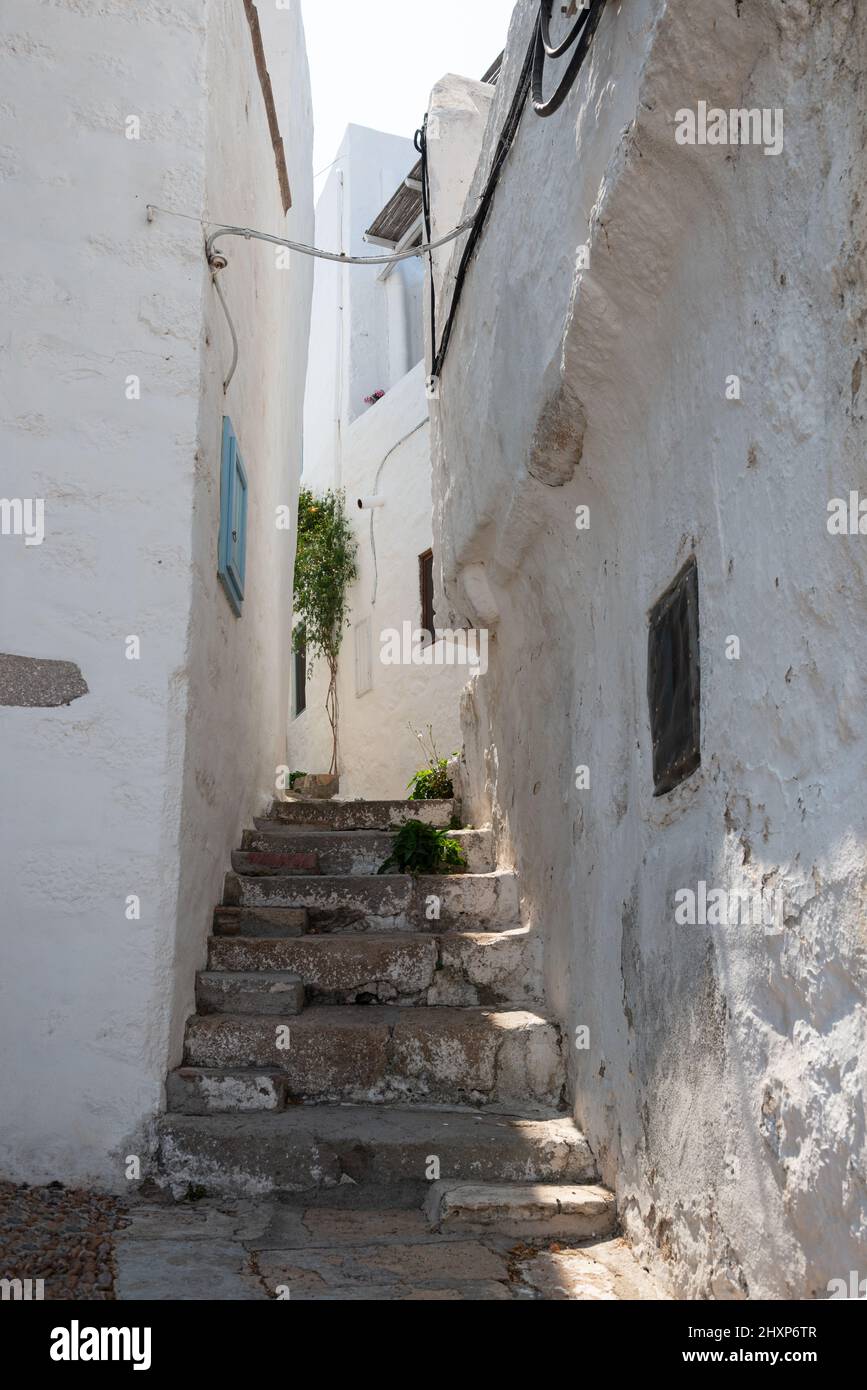 Enge Gasse in Chora der Insel Patmos mit steilen Treppen, die zwischen weiß getünchten Wänden hinaufführen Stockfoto