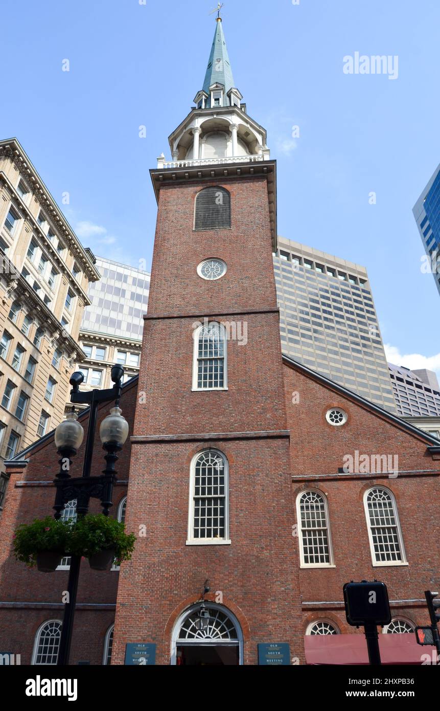 Das Old South Meeting House mitten in Boston mit Straßenlaterne im Vordergrund und einigen Wolkenkratzern im Hintergrund mit blauem Himmel Stockfoto