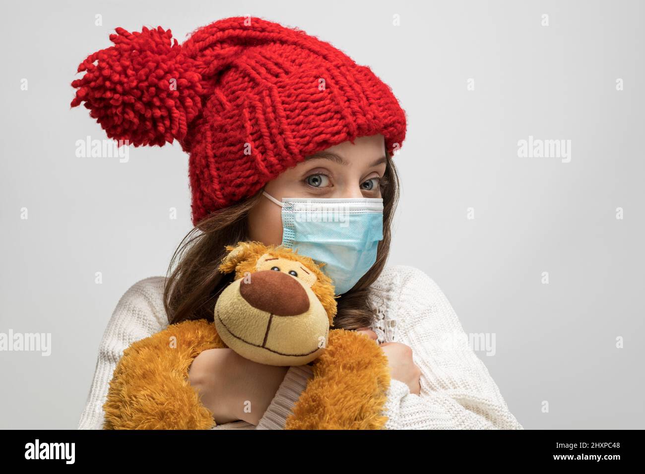 Teenager mit Teddybär, Maske und rotem Hut Stockfoto