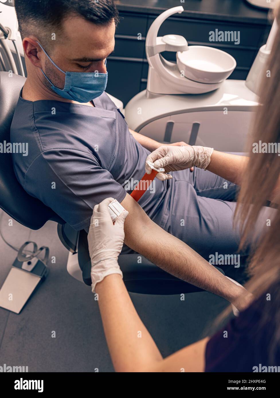 Die Krankenschwester legt vor der Blutentnahme einen Abfluss auf den Arm des Patienten an Stockfoto