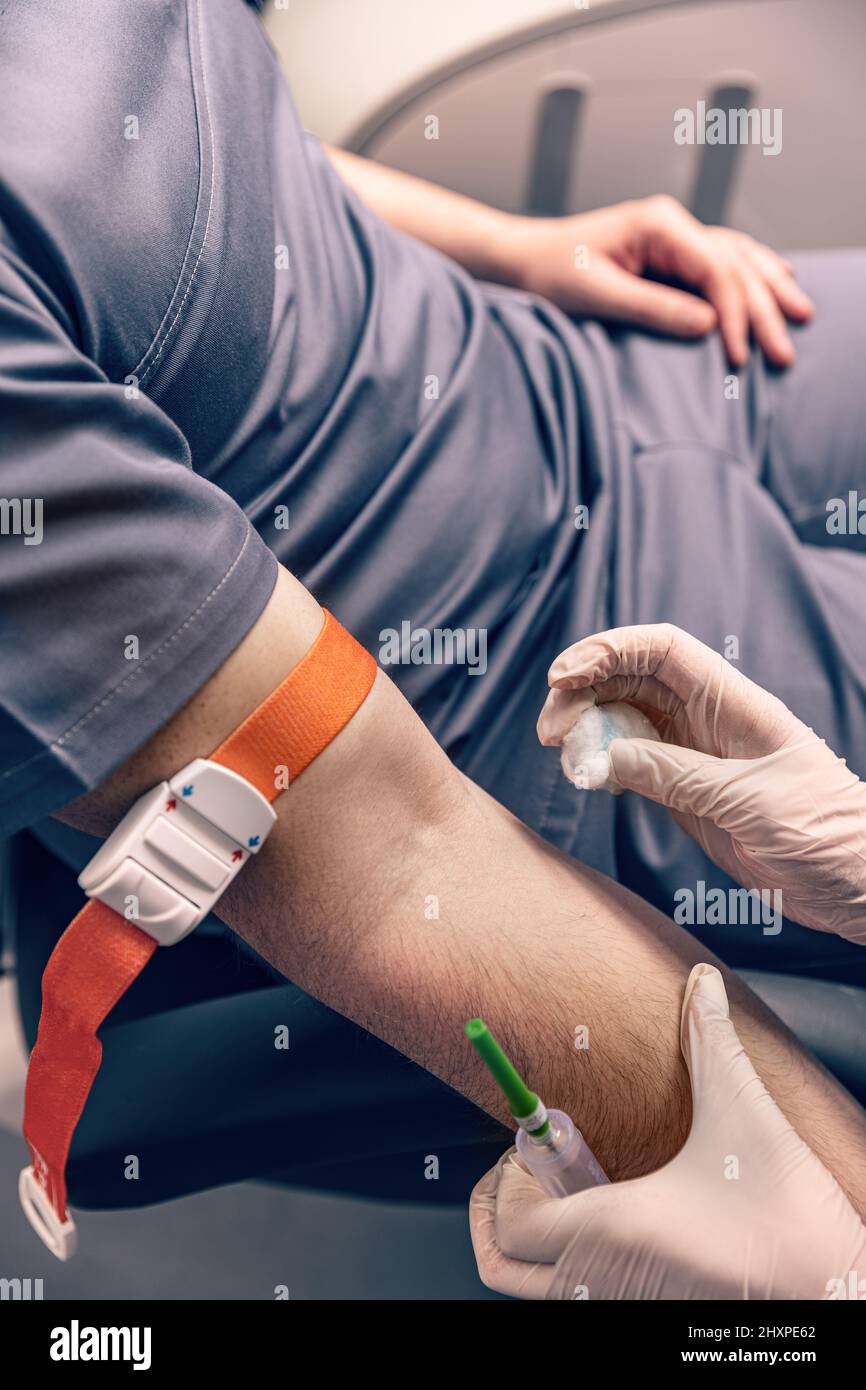 Krankenschwester, die den männlichen Arm vor dem Bluttest desinfiziert. Stockfoto