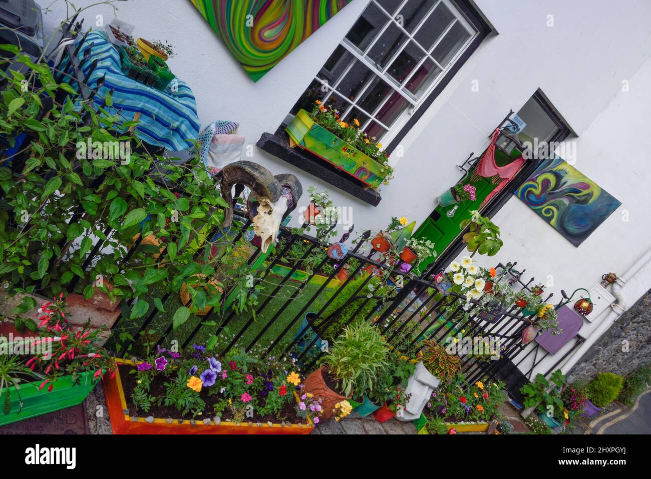 Kompakter Garten vor einer Hütte, mit Geländern, Astrorasen und Gemälden an den Wänden. Stockfoto