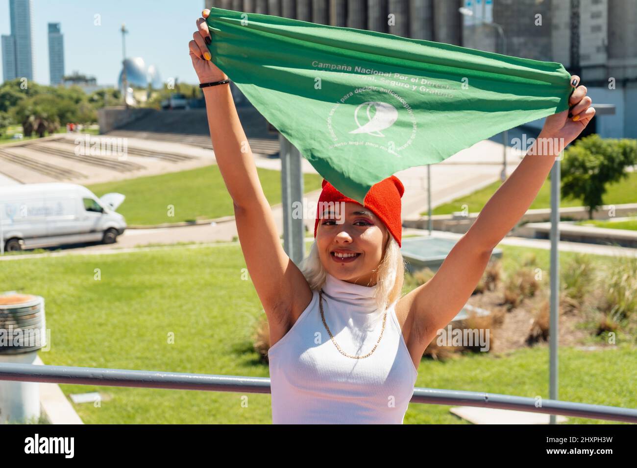 Schöne junge Aktivistin, die einen grünen Schal aufhebt, der den feministischen Kampf für Gleichheit und legale Abtreibung in Lateinamerika symbolisiert. Legal, sicher Stockfoto