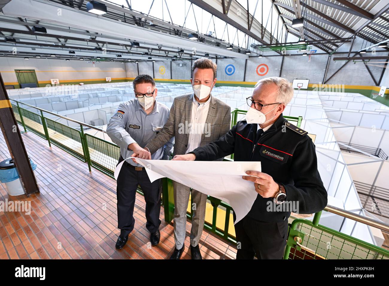 Ravensburg, Deutschland. 14. März 2022. Harald Sievers (CDU, M), Landrat des Kreises Ravensburg, Bezirksfeuerwehrchef Oliver Surbeck (r) und Kevin Kärcher vom Technischen Hilfswerk Ravensburg schauen sich die neu geschaffene Unterkunft in der Burachhalle an. Eine Wohnfläche hat 16 Quadratmeter und bis zu sechs Schlafmöglichkeiten. Quelle: Felix Kästle/dpa/Alamy Live News Stockfoto