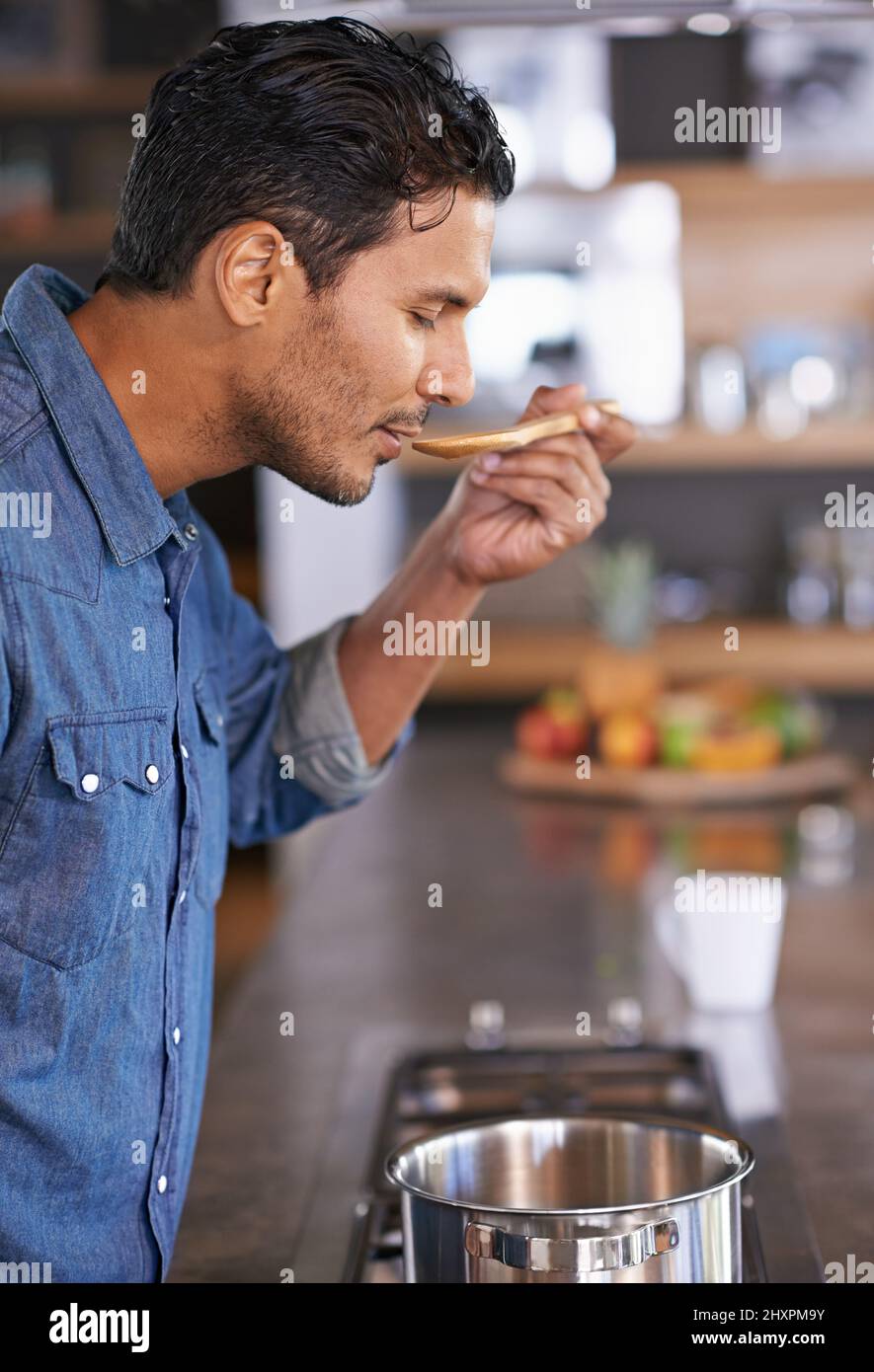 Meine Mütter Rezepte sind immer die besten. Aufnahme eines gutaussehenden Mannes, der Essen schmeckte, während er heamp039s zu Hause kochte. Stockfoto