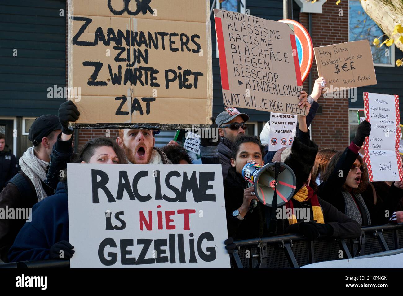 Mehrere Personen, die als Zwarte Piet verkleidet waren, passieren vor der Demonstration der antirassistischen Gruppe in Zaandam Stockfoto