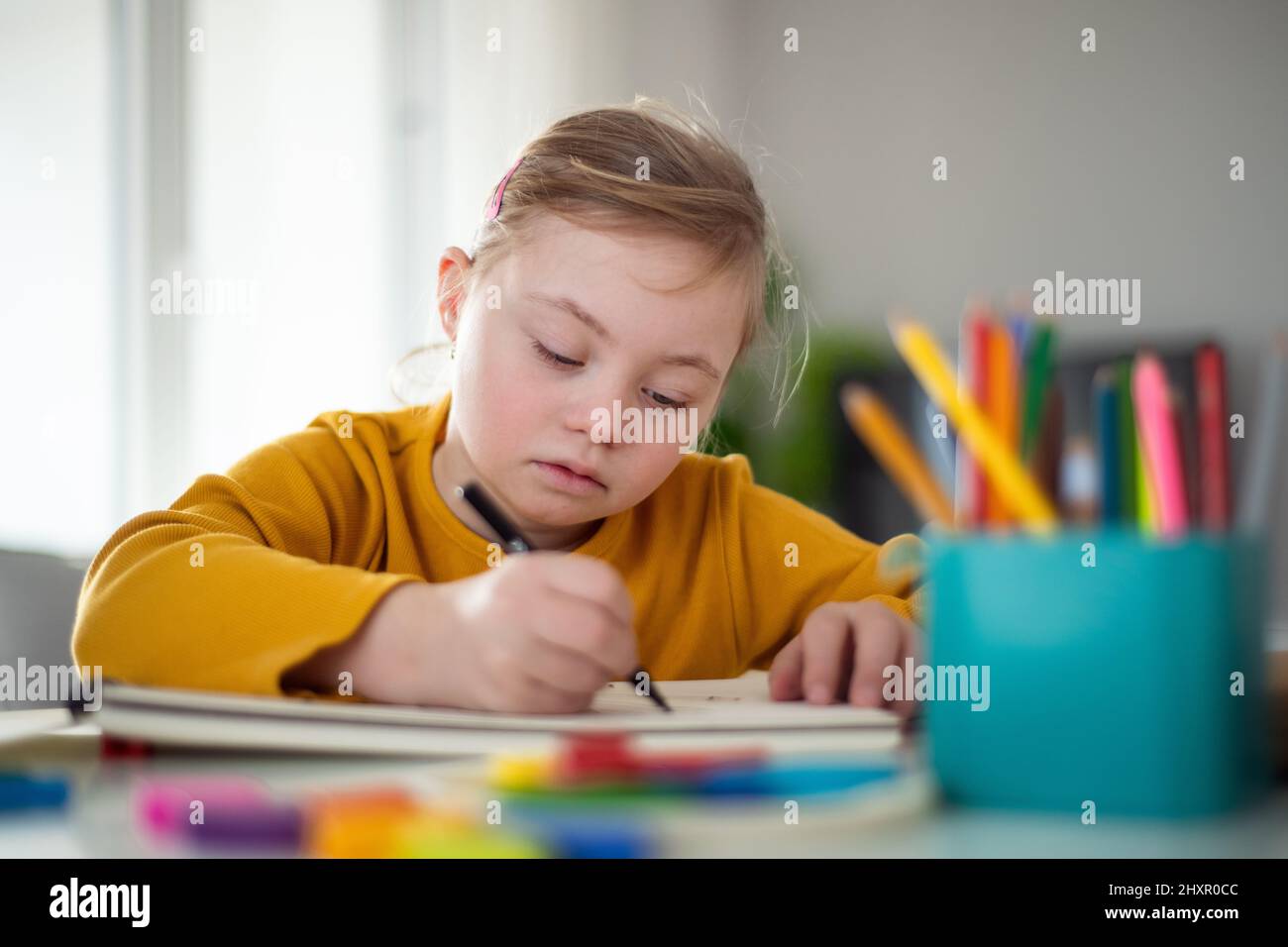 Kleines Mädchen mit Down-Syndrom Zeichnung zu Hause. Stockfoto