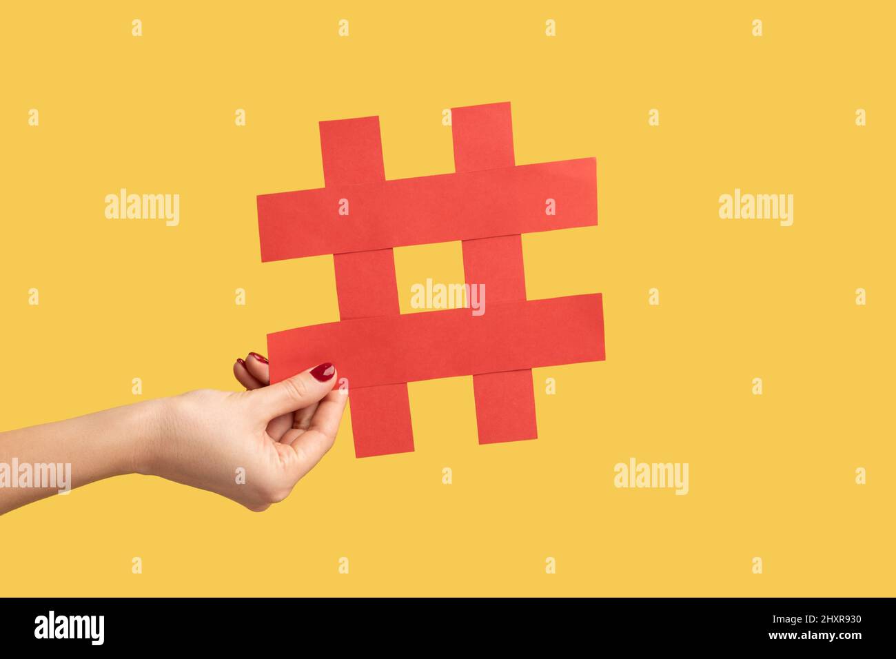Nahaufnahme einer Frau mit einem großen Hashtag-Symbol aus rotem Papier, Hashzeichen berühmter Medieninhalte, Social Media Marketing und Blog-Werbung. Innenaufnahme des Studios isoliert auf gelbem Hintergrund. Stockfoto