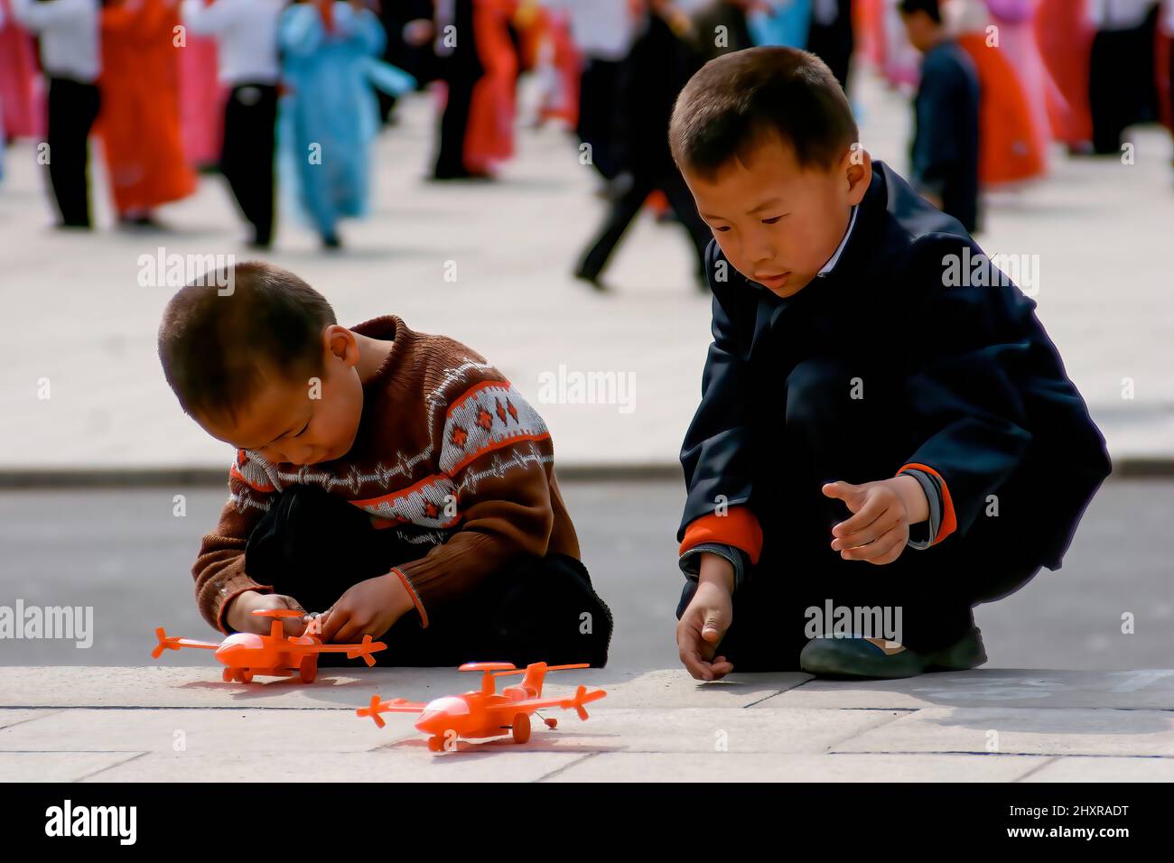 Kinder, die auf einem Platz in Pjöngjang, Nordkorea, mit Plastikflugzeugen spielen Stockfoto