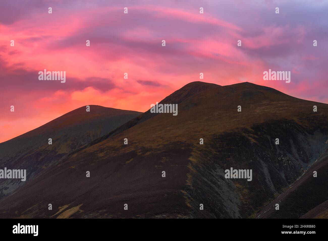 Leuchtend rosa und lila Sonnenuntergang leuchtenden Himmel über Lake District Bergkette an einem schönen Sommerabend. Stockfoto