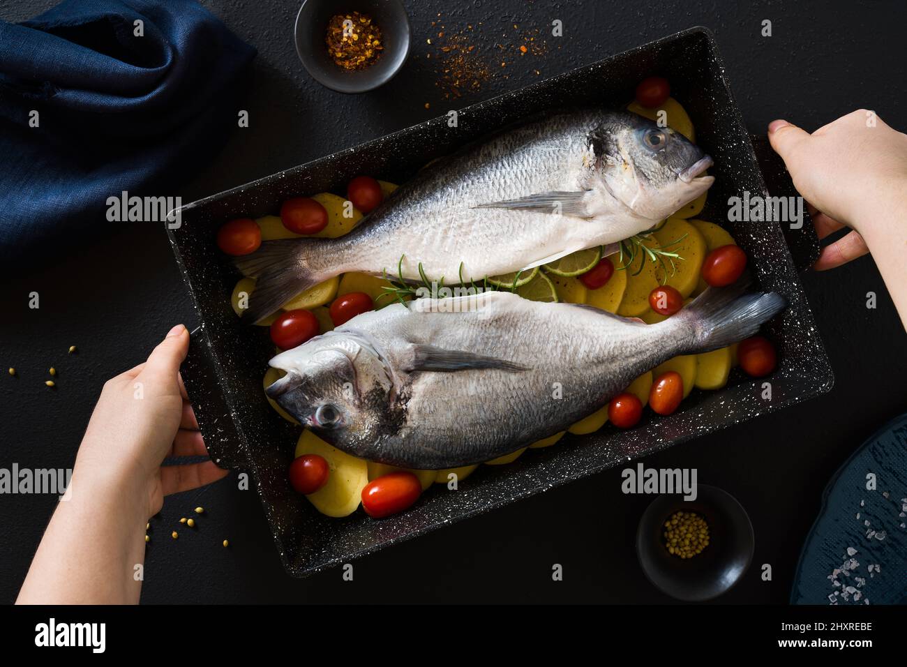 Fisch in einem Backblech mit Kartoffeln und Tomaten, fertig zum Backen  Stockfotografie - Alamy