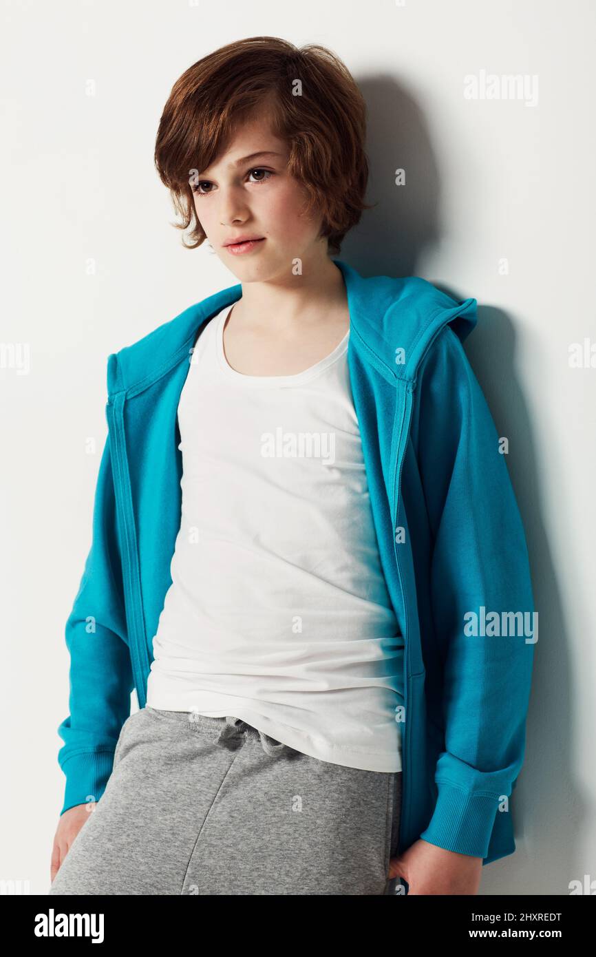 Bequem in seiner Jogginghose. Niedlicher Teenager-Junge trägt lässige Kleidung, während er auf Weiß isoliert ist. Stockfoto