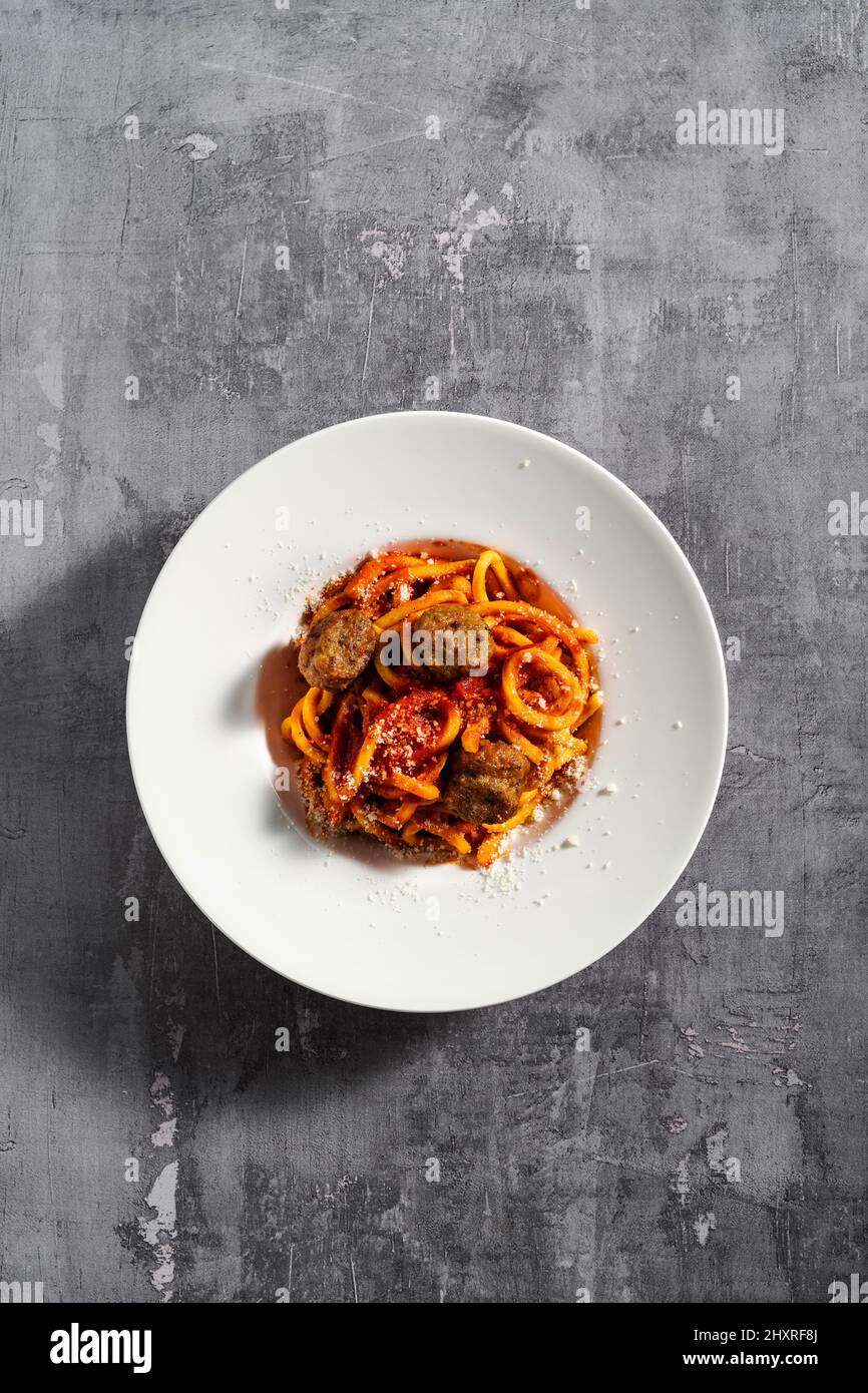 Hausgemachte Spaghetti mit Tomatensauce, Parmesan und Fleischbällchen auf dunklem Hintergrund Stockfoto