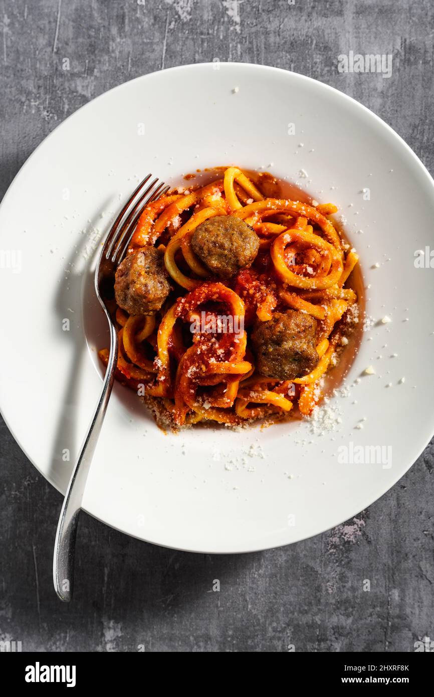 Hausgemachte Spaghetti mit Tomatensauce, Parmesan und Fleischbällchen auf dunklem Hintergrund Stockfoto