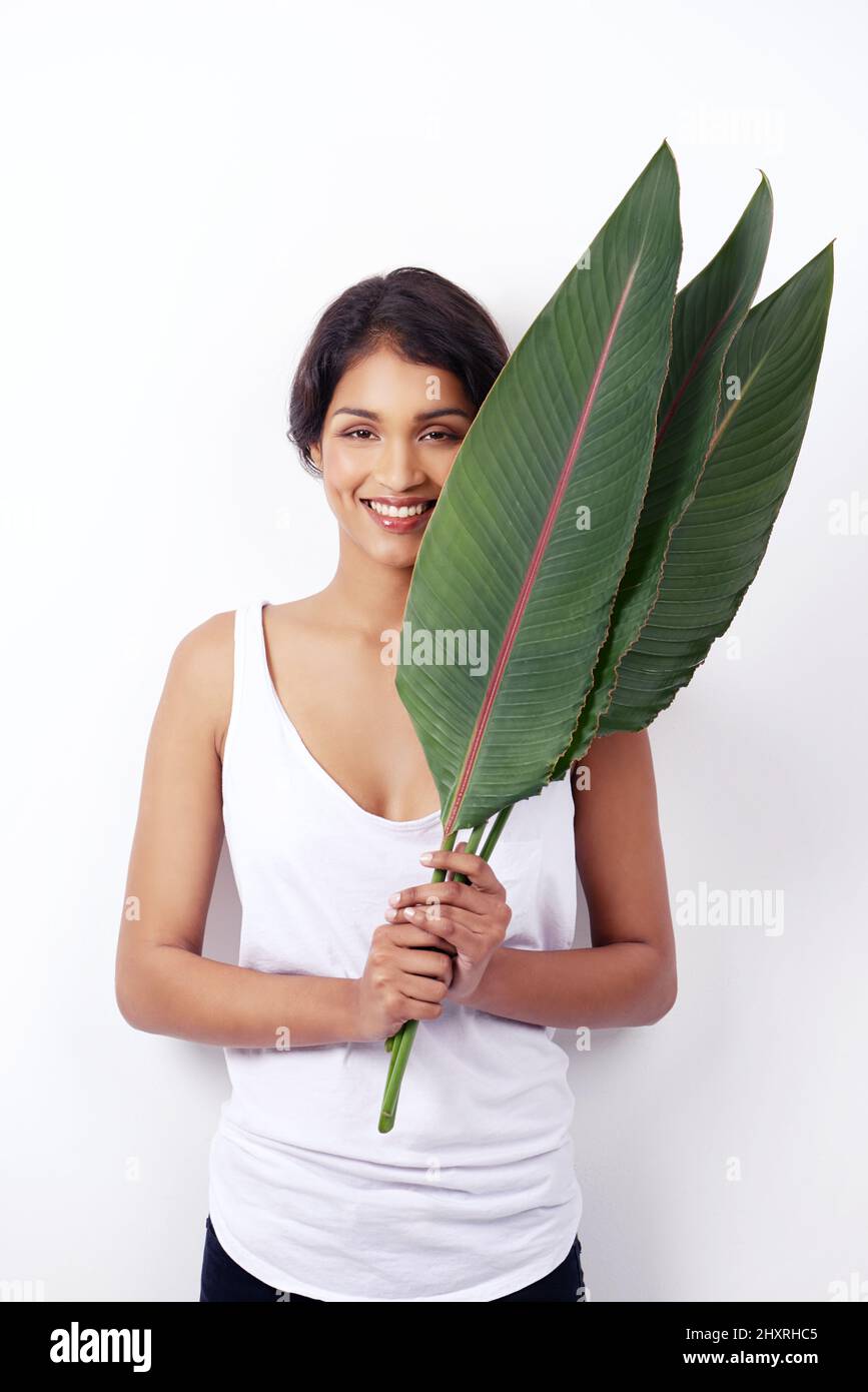 Palmenschönheit. Studioaufnahme einer attraktiven jungen ethnischen Frau mit Palmwedeln. Stockfoto