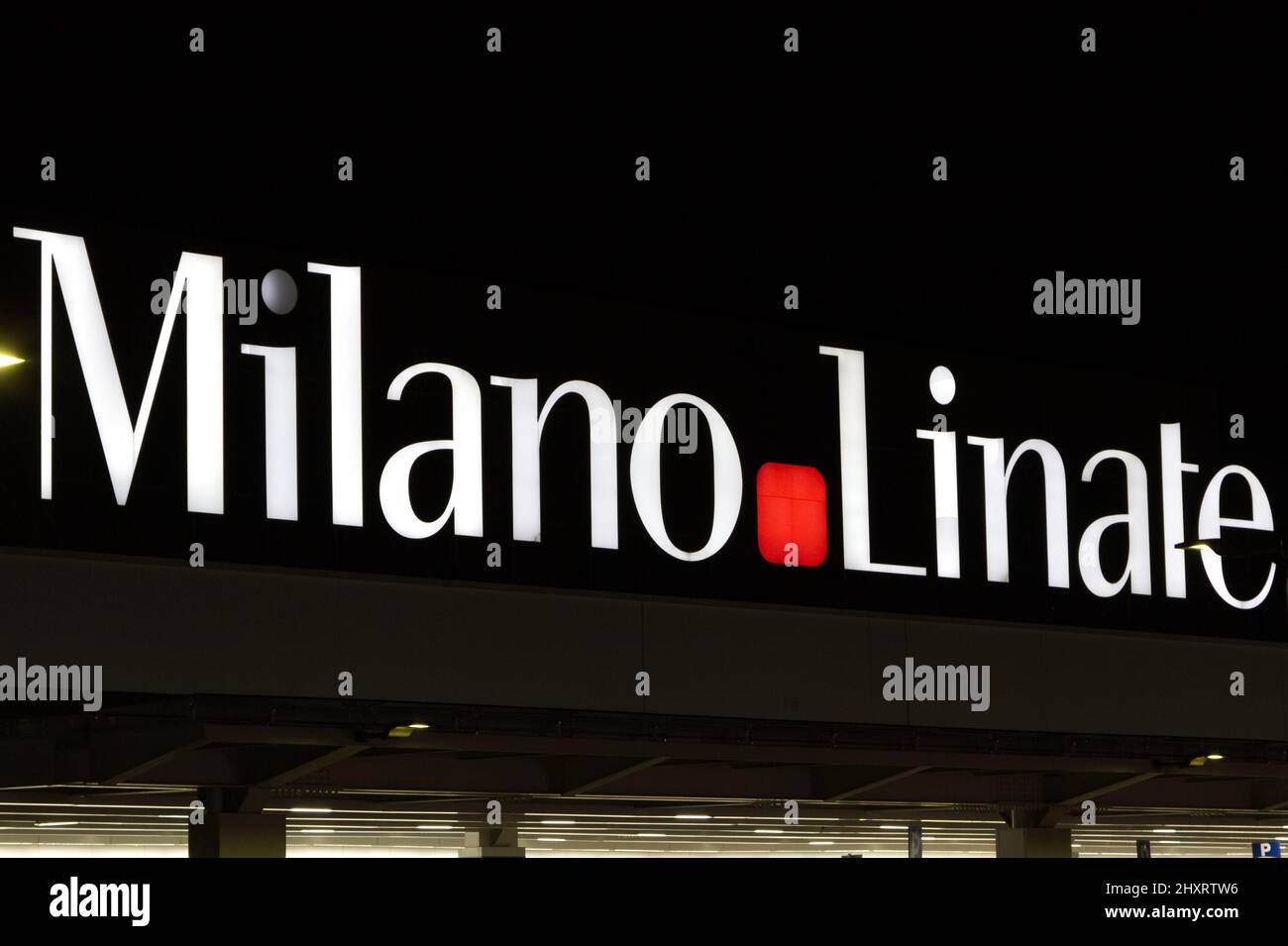 Beleuchtete Beschilderung auf der Vorderseite des Terminalgebäudes des Flughafens Milano Linate bei Nacht Stockfoto