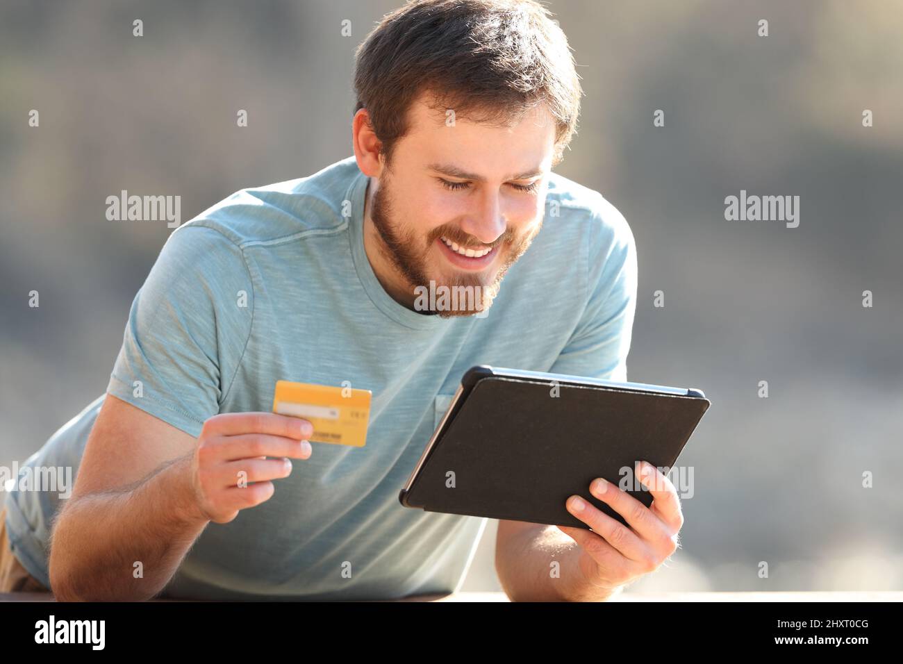 Glücklicher Mann, der online mit Kreditkarte und Tablet im Freien kauft Stockfoto