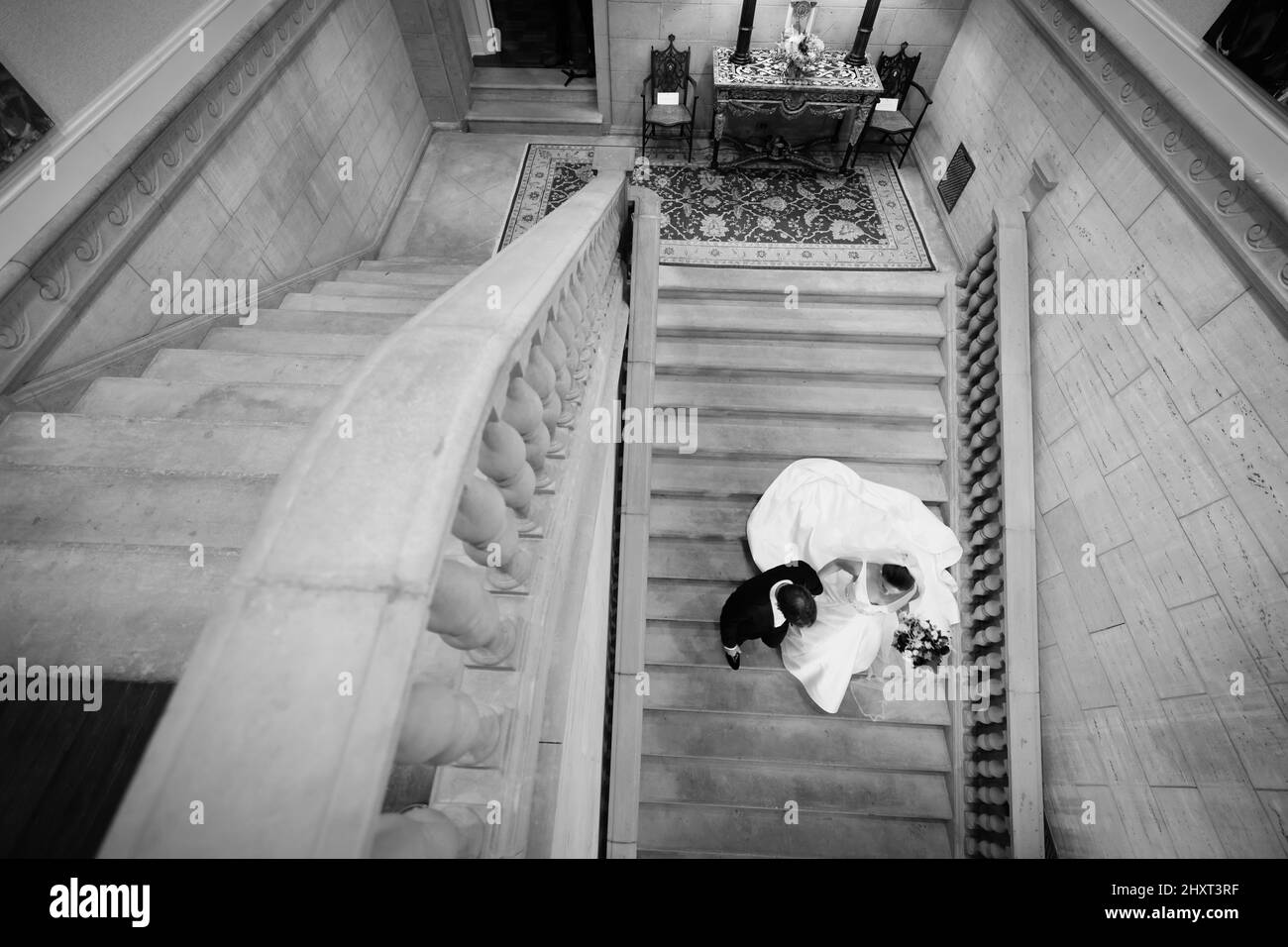 Grauer Blick von oben auf eine Braut und einen Bräutigam, der die Steintreppe hinunterklettert Stockfoto