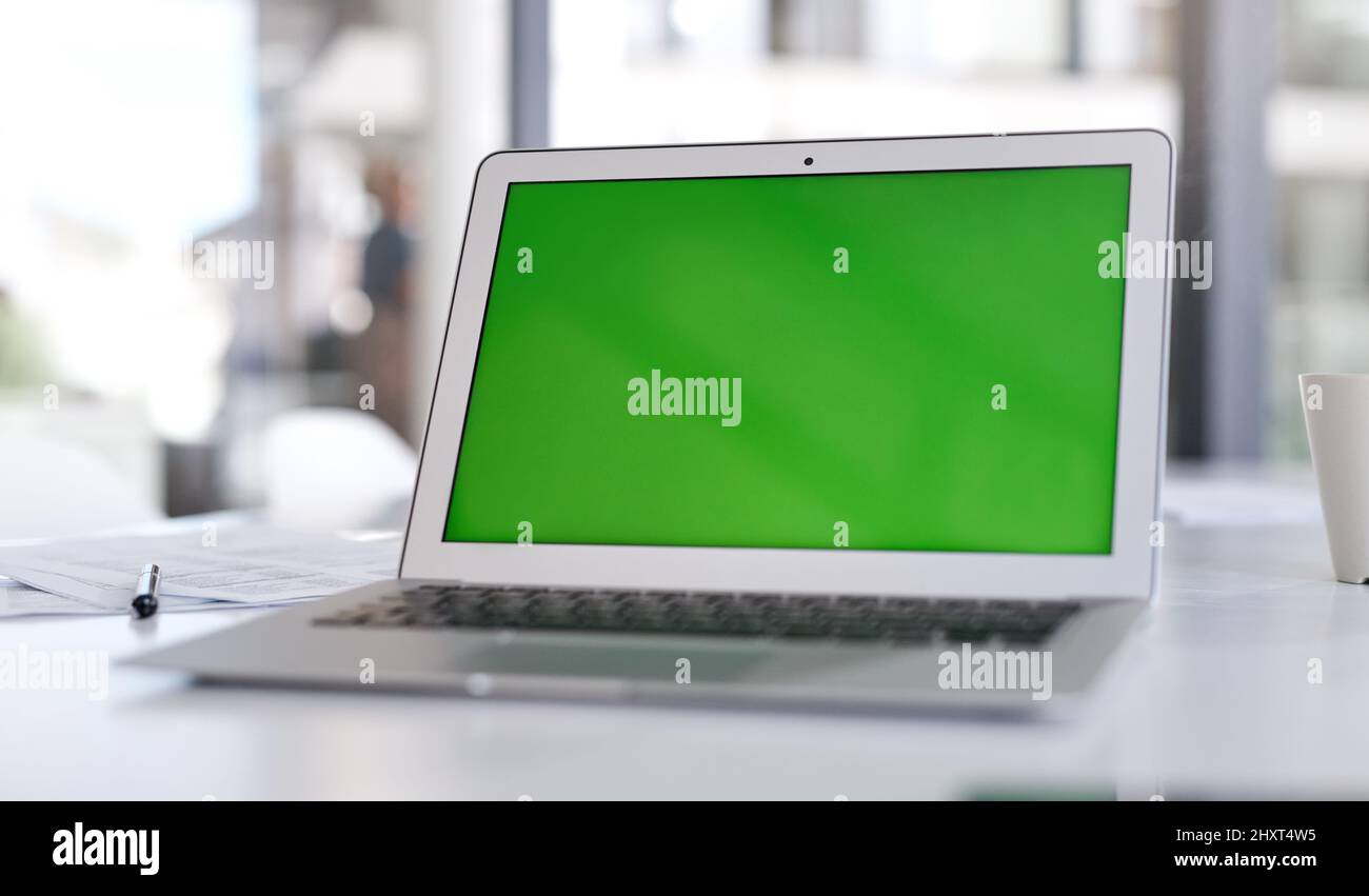 Achte darauf, dass deine Landing Page die lauteste Aussage macht. Aufnahme eines Laptops mit einem grünen Bildschirm auf einem Schreibtisch in einem modernen Büro. Stockfoto