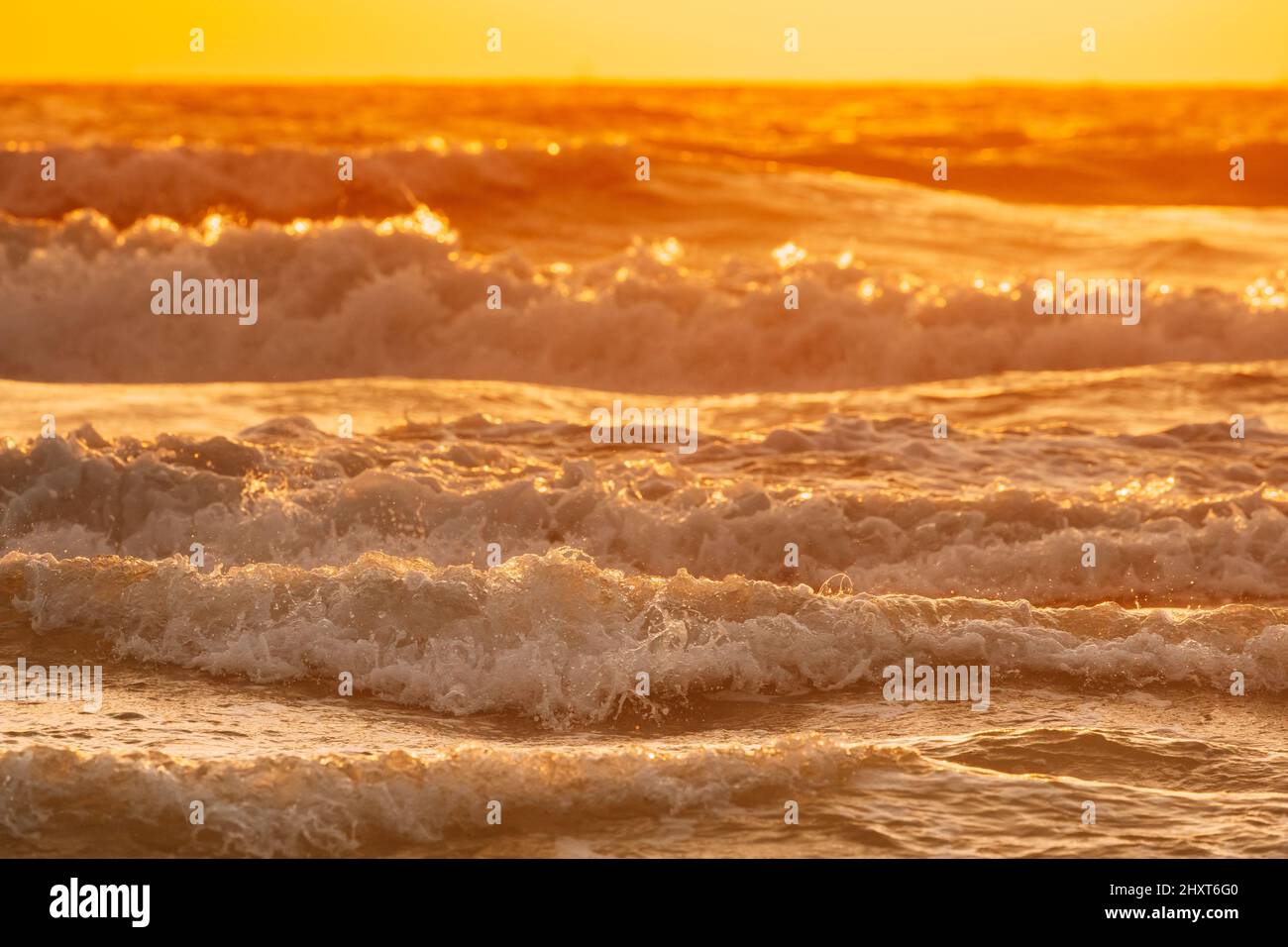 Meerwasseroberfläche bei Sonnenuntergang. Natürlicher Sonnenaufgang warme Farben des Ozeans. Meeresoberfläche mit schäumenden Wellen bei Sonnenuntergang. Abendsonne Sonnenschein Stockfoto