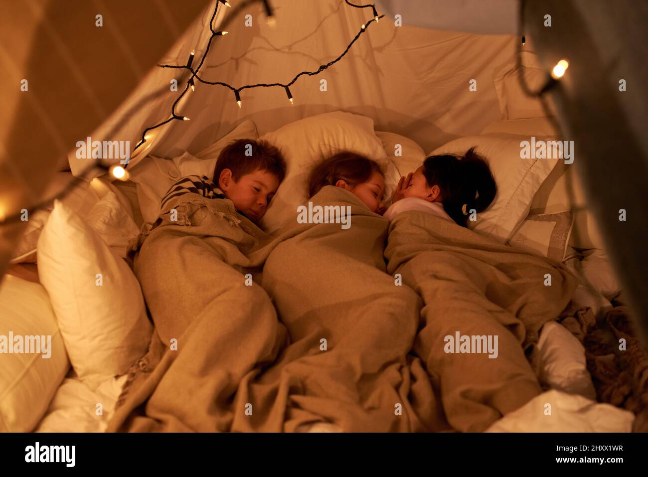 Schlafende kleine Engel. Aufnahme von drei kleinen Kindern, die in einem Bettelzelt schlafen. Stockfoto