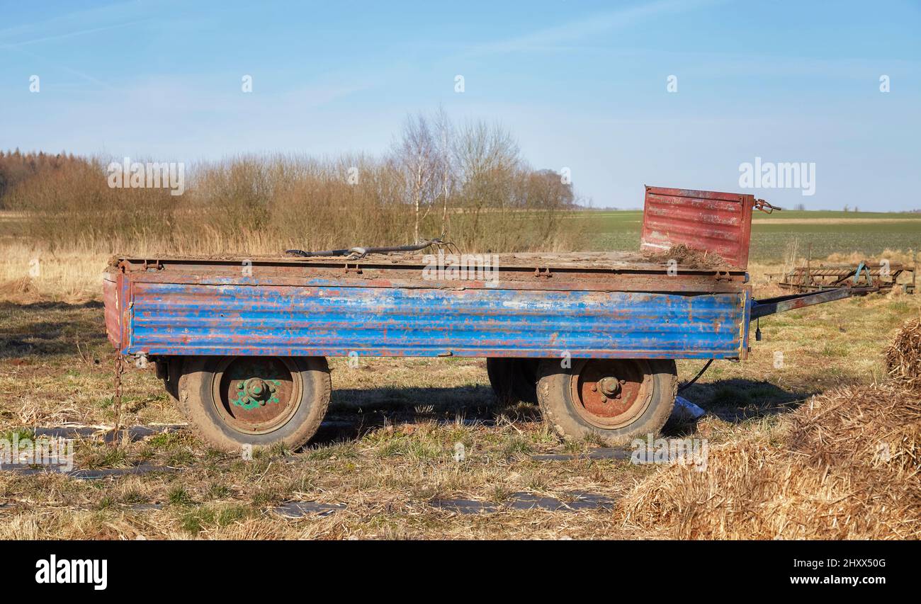 Ein alter leerer Traktoranhänger auf einem Feld. Stockfoto