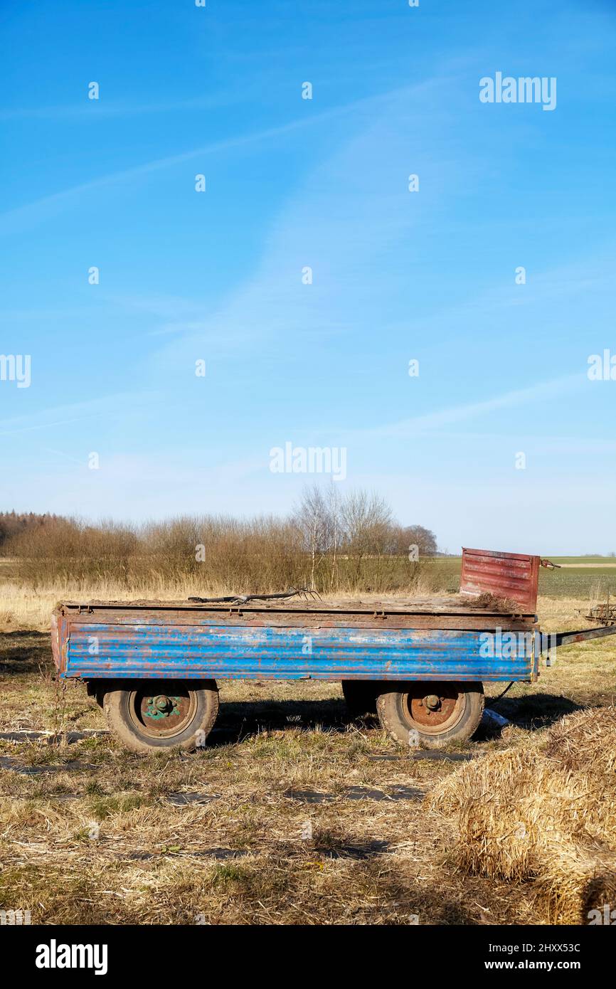 Ein alter leerer Traktoranhänger auf einem Feld. Stockfoto