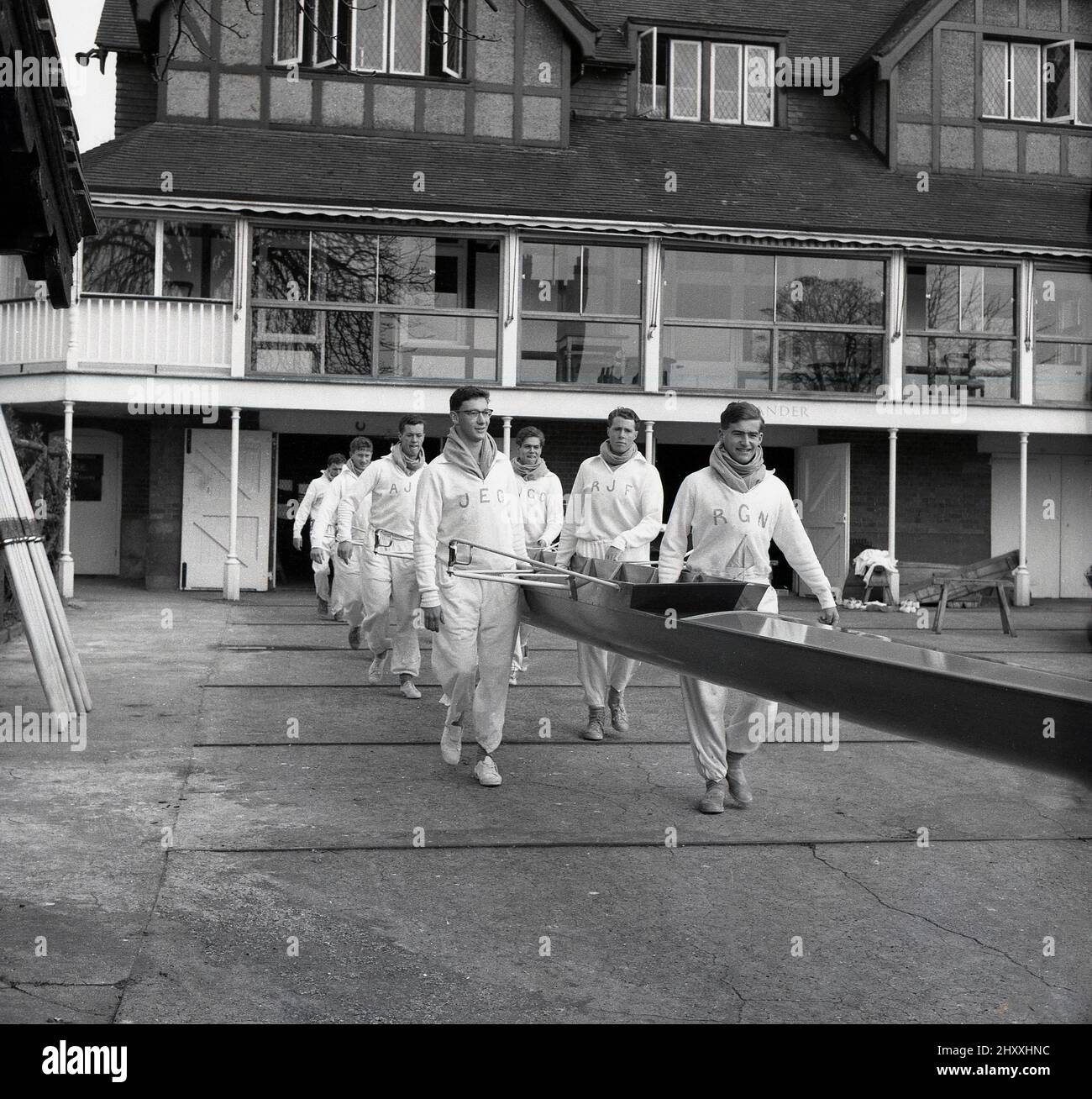 1961, historisch, die Crew des Cambridge University Boat Clubs, die ihr langes Ruderschiff aus dem Bootshof des Leander Clubs transportiert, für eine Trainingseinheit für das bevorstehende Oxford und Cambridge Boat Race. Ein berühmtes University Rudern Rennen begann im Jahr 1829 und ein jährliches Ereignis auf der Themse, es findet auf der Championship Course zwischen Putney und Barnes im Südwesten Londons. Der 1818 gegründete Leander Club, einer der ältesten Ruderclubs der Welt, baute 1897 sein Clubhaus in Remenham am Fluss bei Henley-on-Thames. Stockfoto