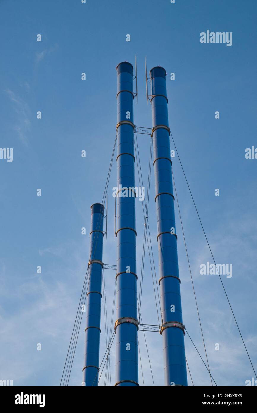 Gruppe von Metallschornsteinen des kleinen lokalen Kraftwerks oder Heizkessels gegen den blauen Himmel. Stockfoto